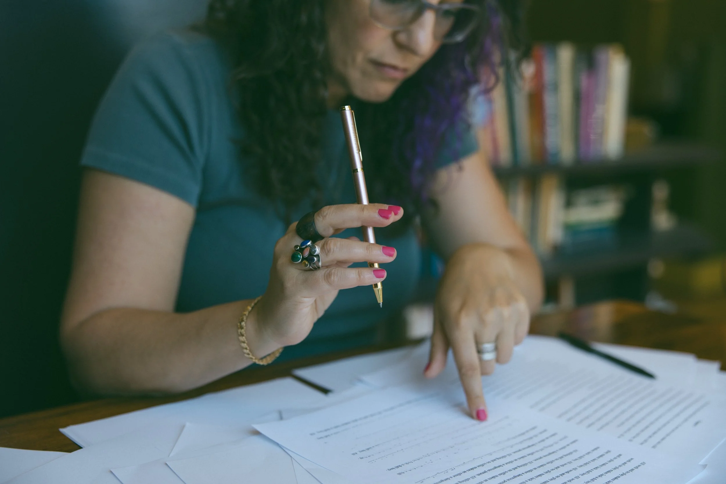 Samantha Pollack, writing coach and editor, holding a rose gold pen and reviewing a manuscript