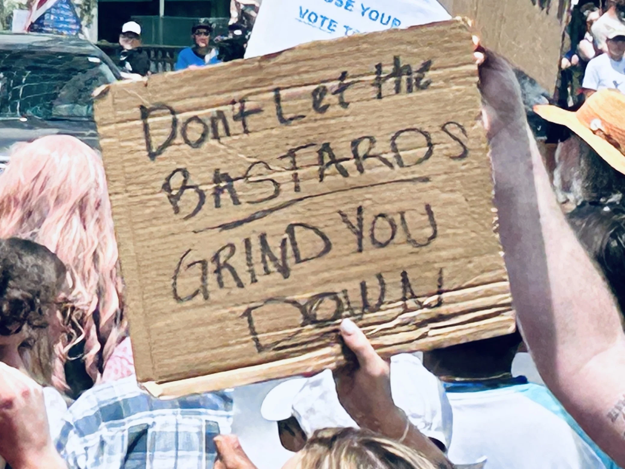 A cardboard sign reading "Don't let the bastards grind you down," No Kings Protest, Asheville, NC, 2025
