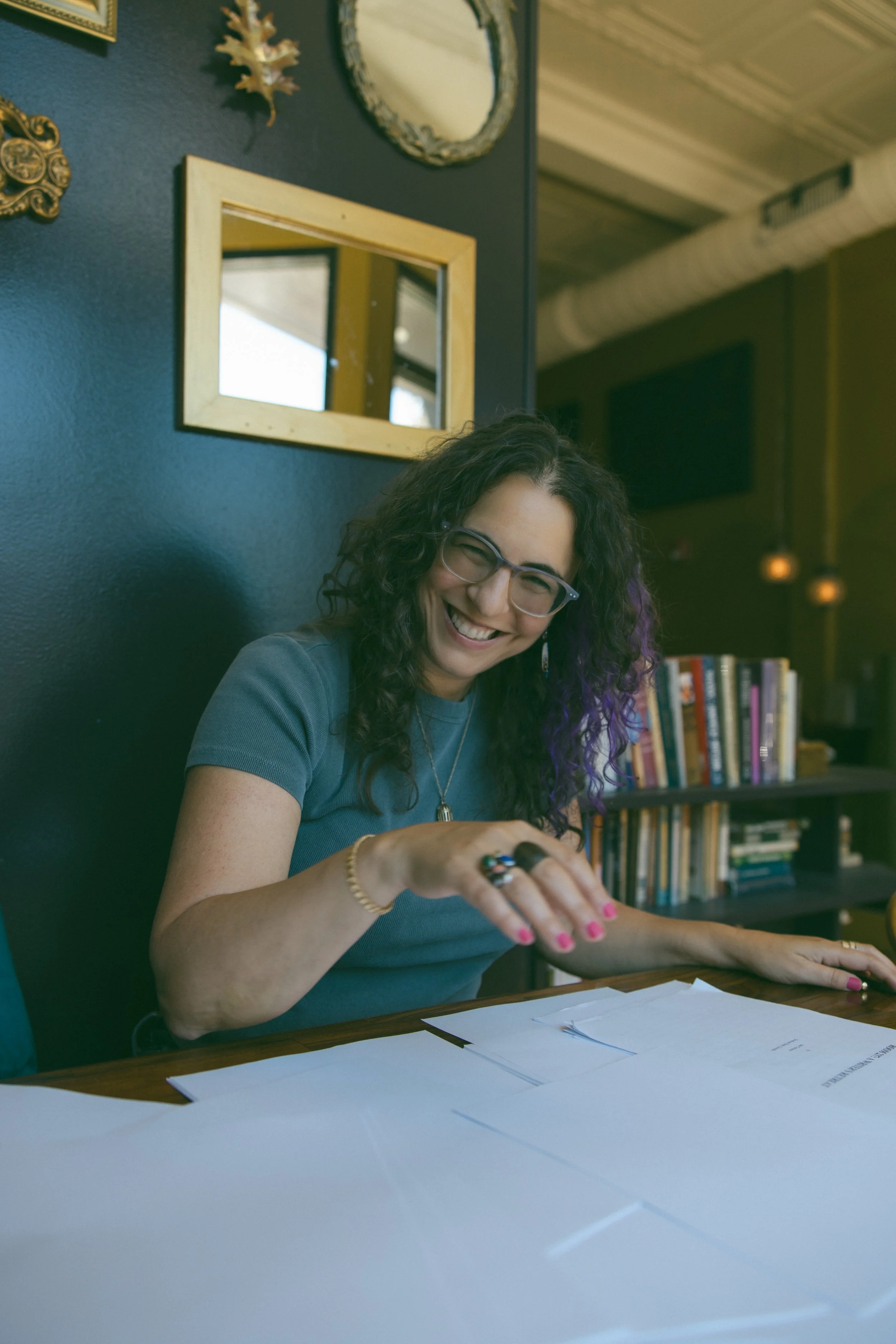 Samantha Pollack, Writing Coach & Editor, reviewing a manuscript in front of a bookshelf