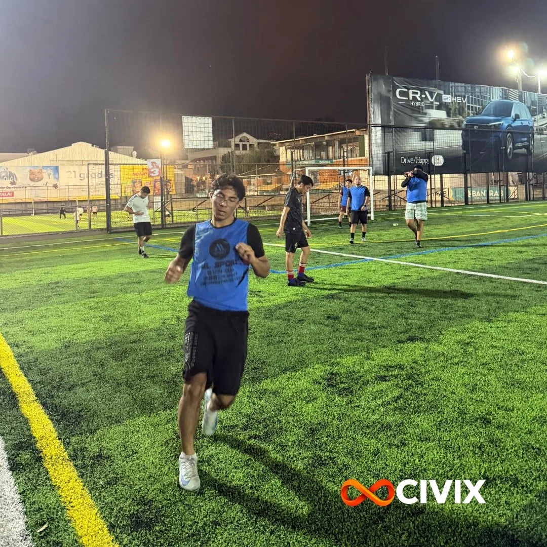 Jóvenes corriendo en un campo de fútbol artificial, en la noche, con vallas y anuncios publicitarios al fondo, algunos usando ropa deportiva y otros con camisetas de entrenamiento. Logo de CIVIX en la esquina inferior derecha.
