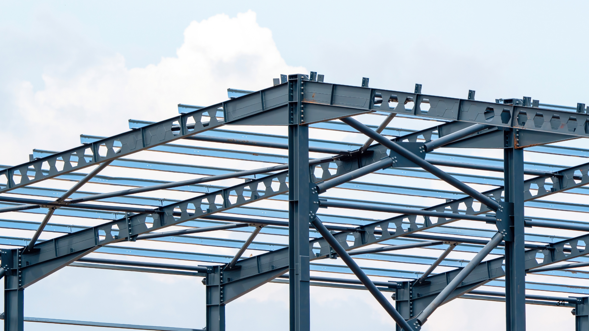 Estructura metálica de una construcción en proceso, con vigas de acero y soportes, bajo cielo nublado.