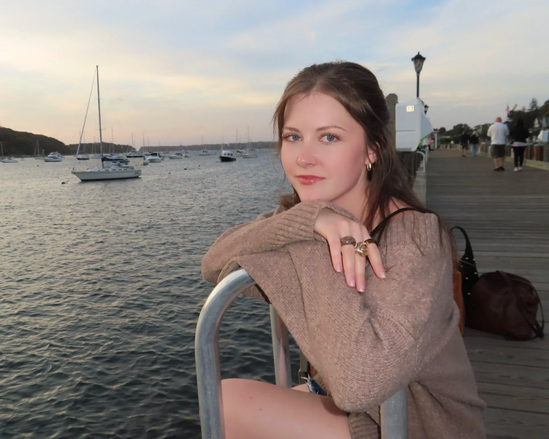 A man with curly dark hair, glasses, and a nose ring looking off to the side in a well-lit room with a white wall and a plant in the background.