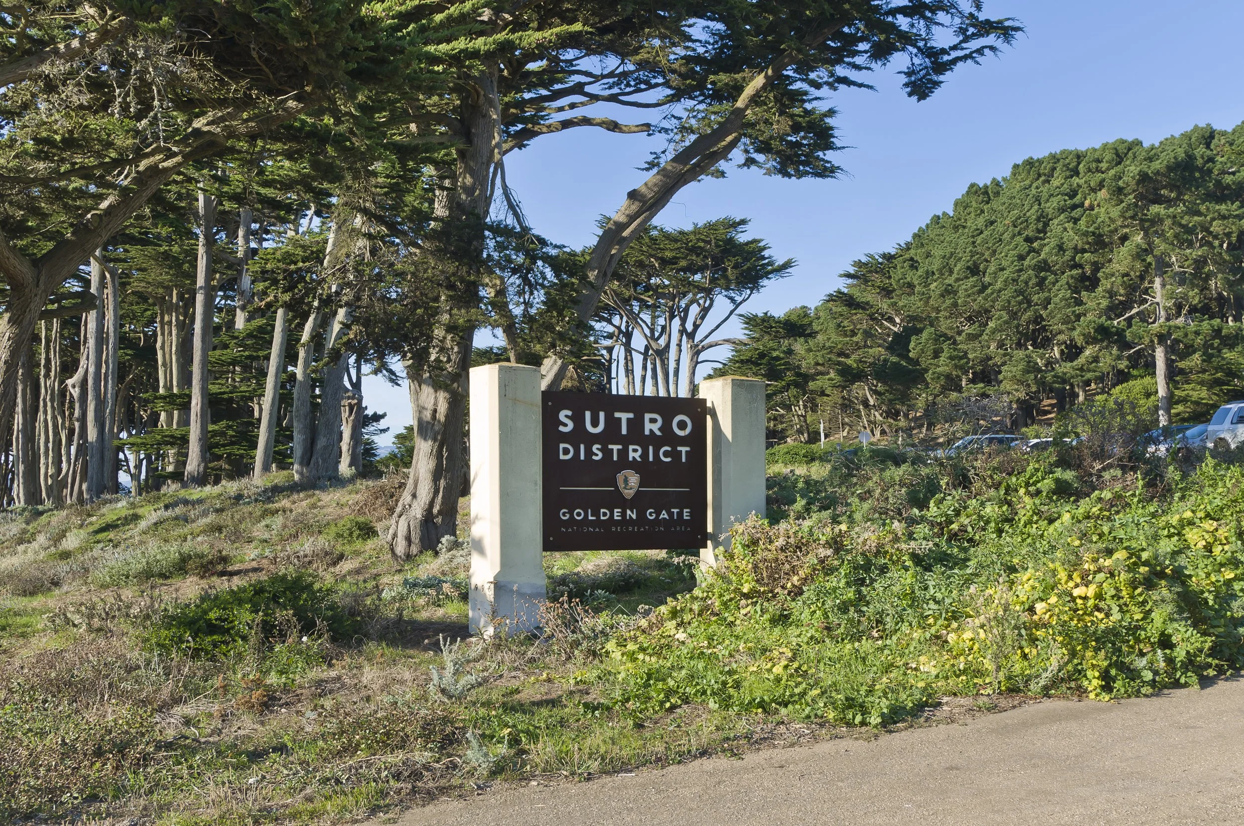 Sign at the entrance of Sutro District in Golden Gate National Recreation Area, surrounded by trees and greenery.