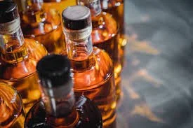 Several bottles of amber liquor on a wooden surface.