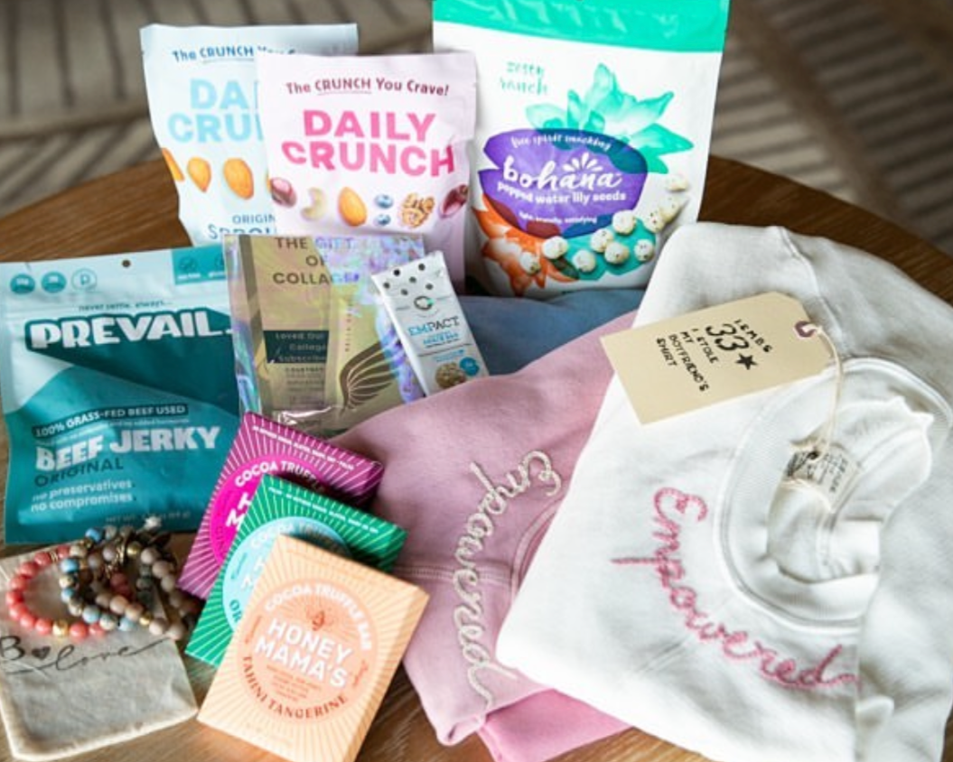 Assorted snacks and gifts displayed on a wooden surface, including beef jerky, candy, snacks, jewelry, and clothing items.