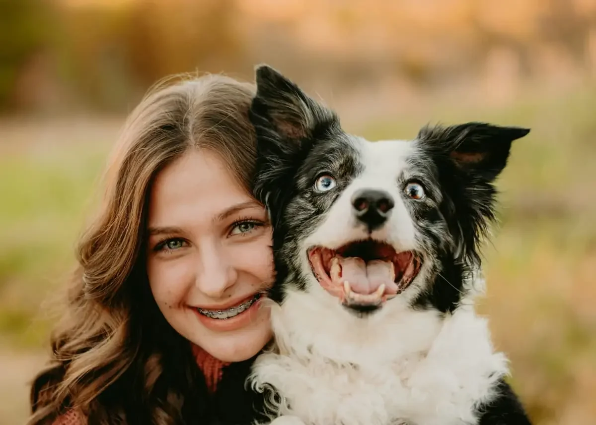 Smiling customer holding a happy dog in backyard.