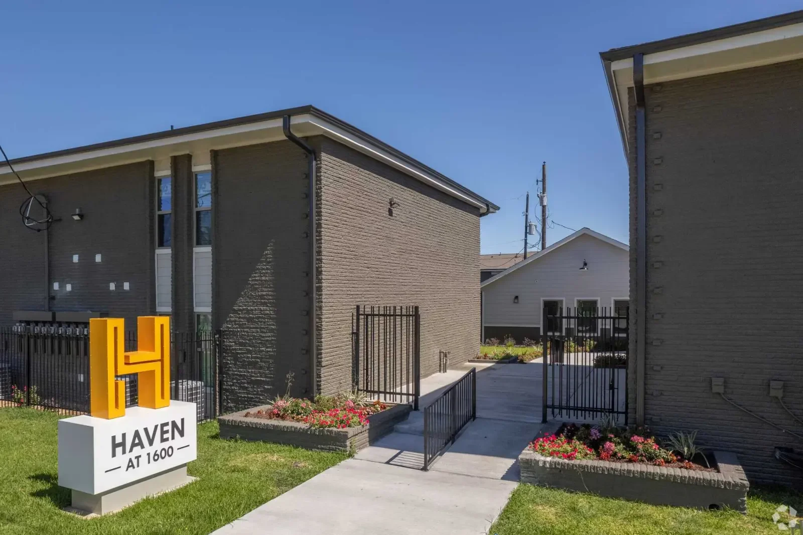A residential complex with modern buildings, a sign that reads 'Haven at 1600,' and landscaped flower beds.