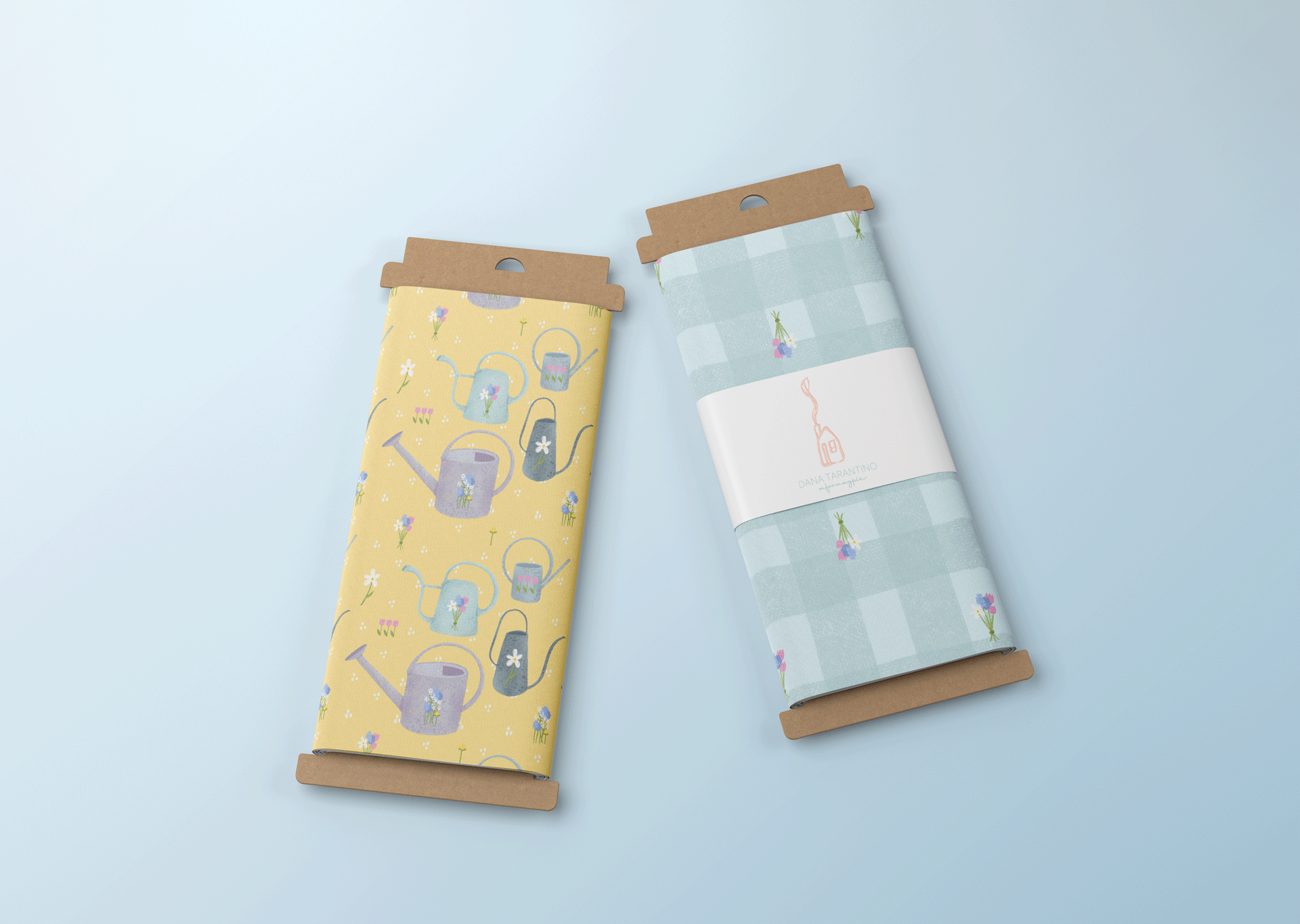 Two packages of wrapping paper, one with a yellow background featuring watering can illustrations, and the other with a blue checkered pattern adorned with small floral designs.