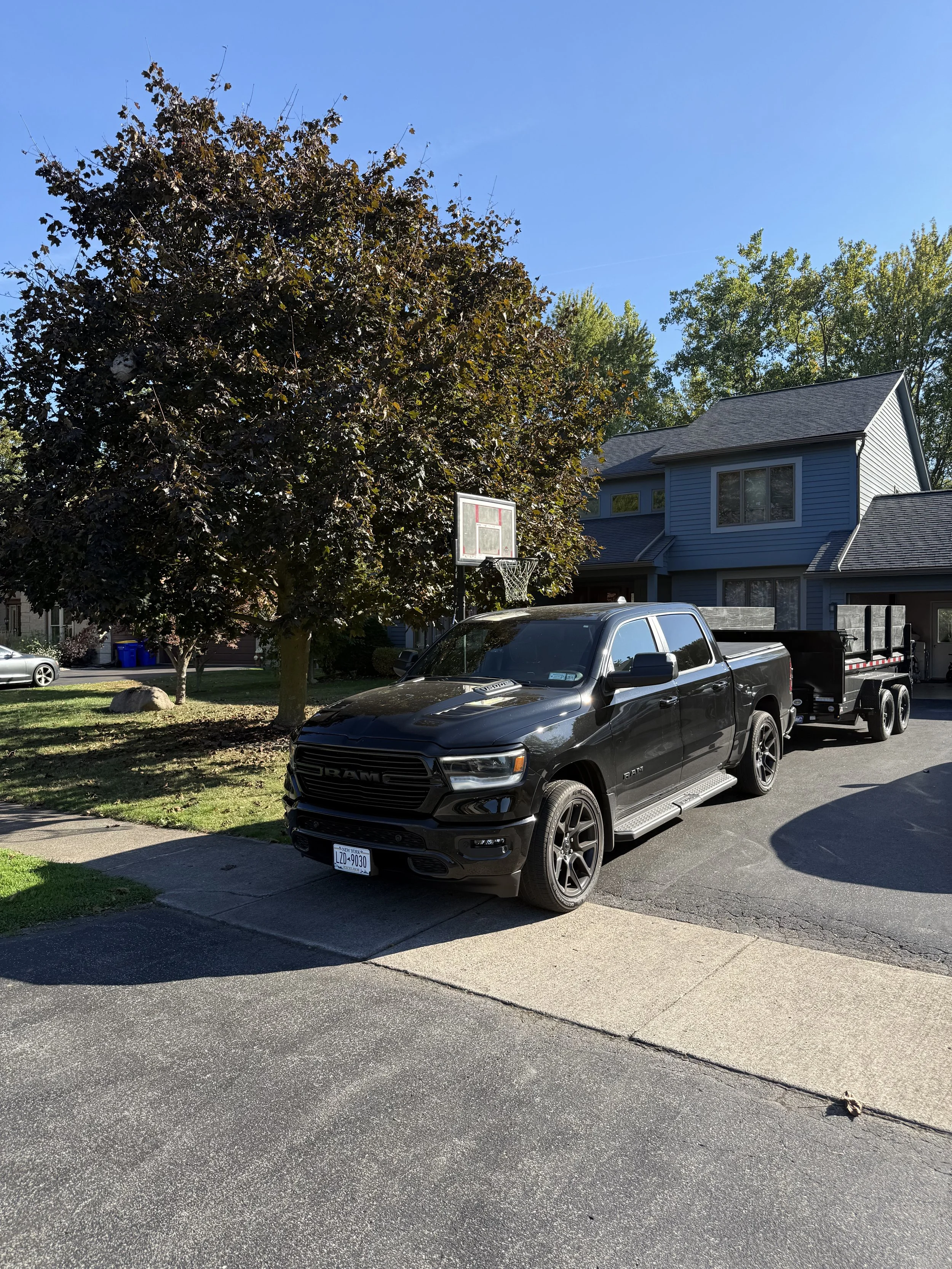 N.A.Z. Junk Removal truck and dump trailer arriving for a same-day cleanout job in a Rochester, NY neighborhood.