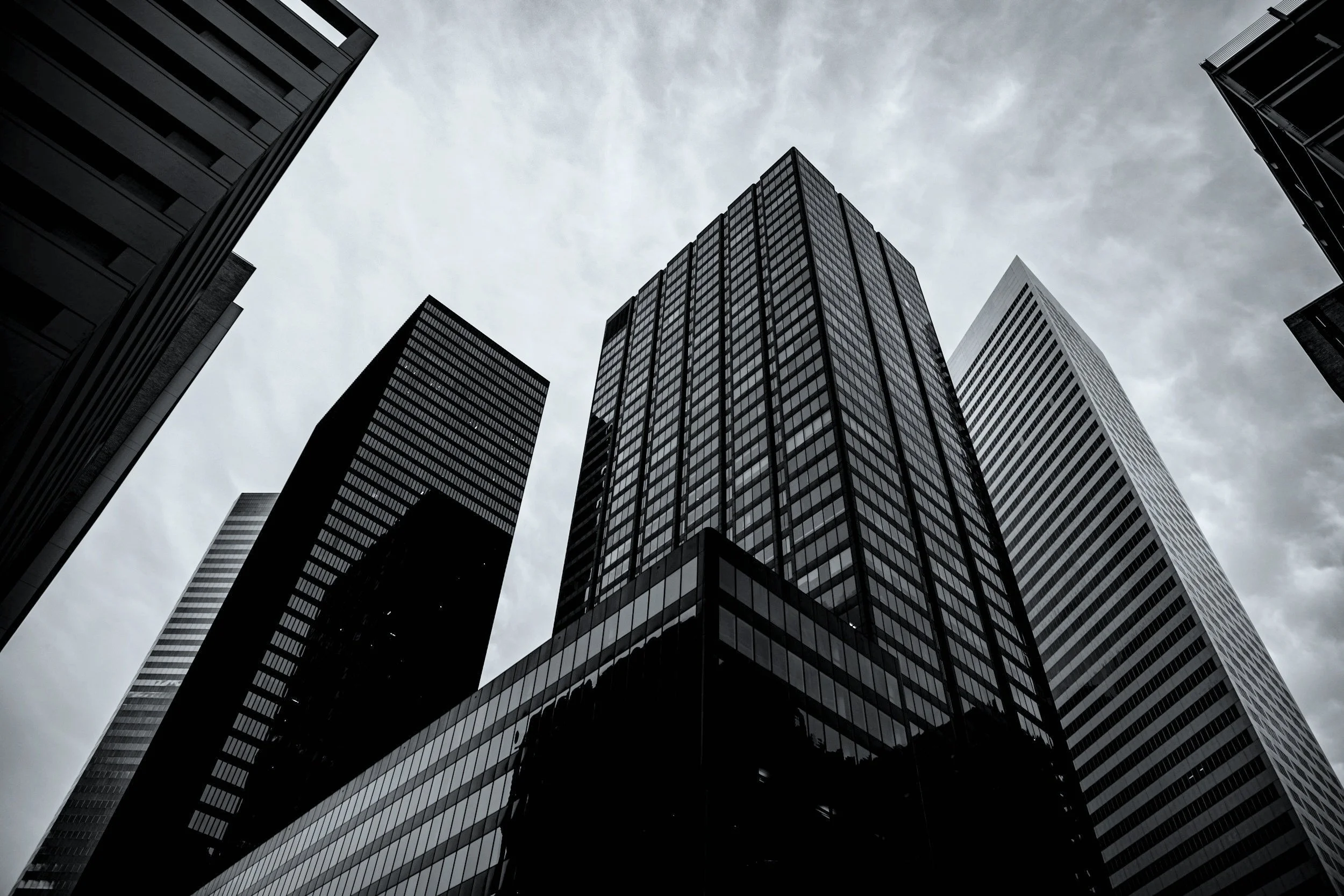 Houston, Texas Tall modern glass skyscrapers viewed from below against a cloudy sky.