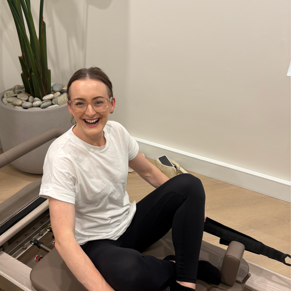 Jazmin Pursell sitting on reformer pilates bed, laughing