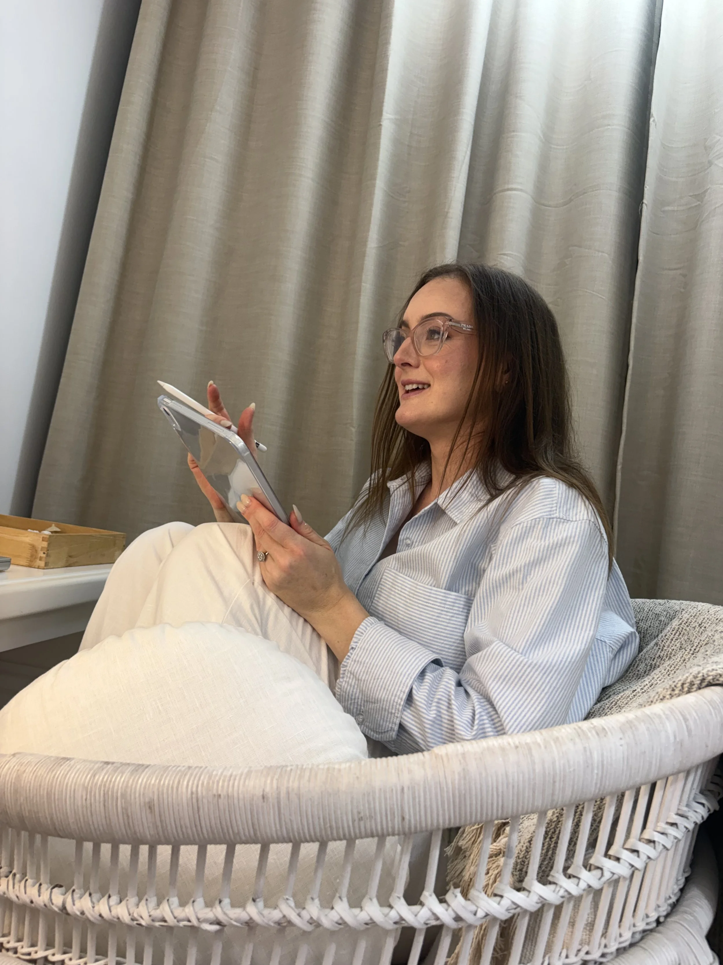Jazmin Pursell sitting on chair, holding iPad, in conversation