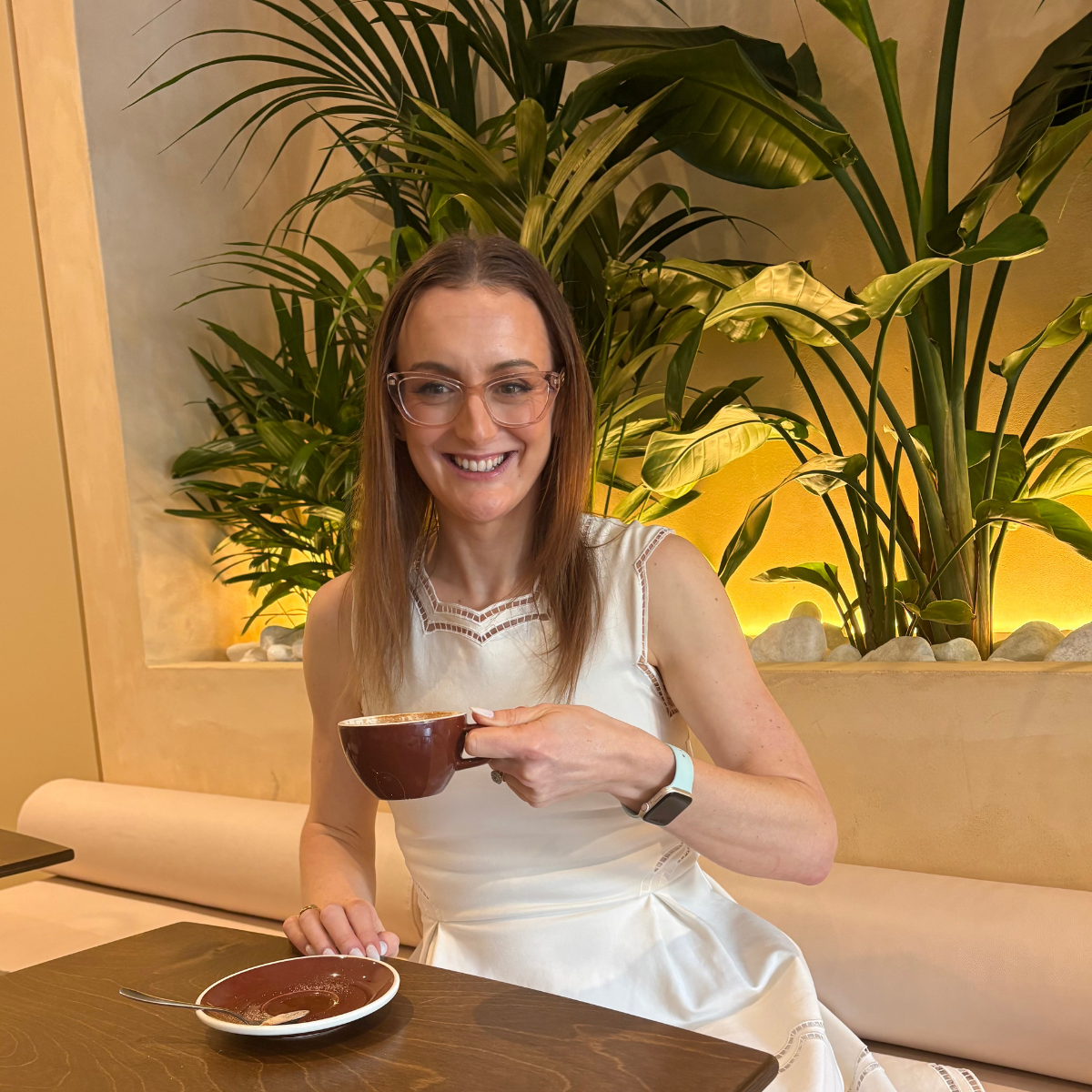 Jazmin Pursell, sitting in a cafe, smiling, holding a tea