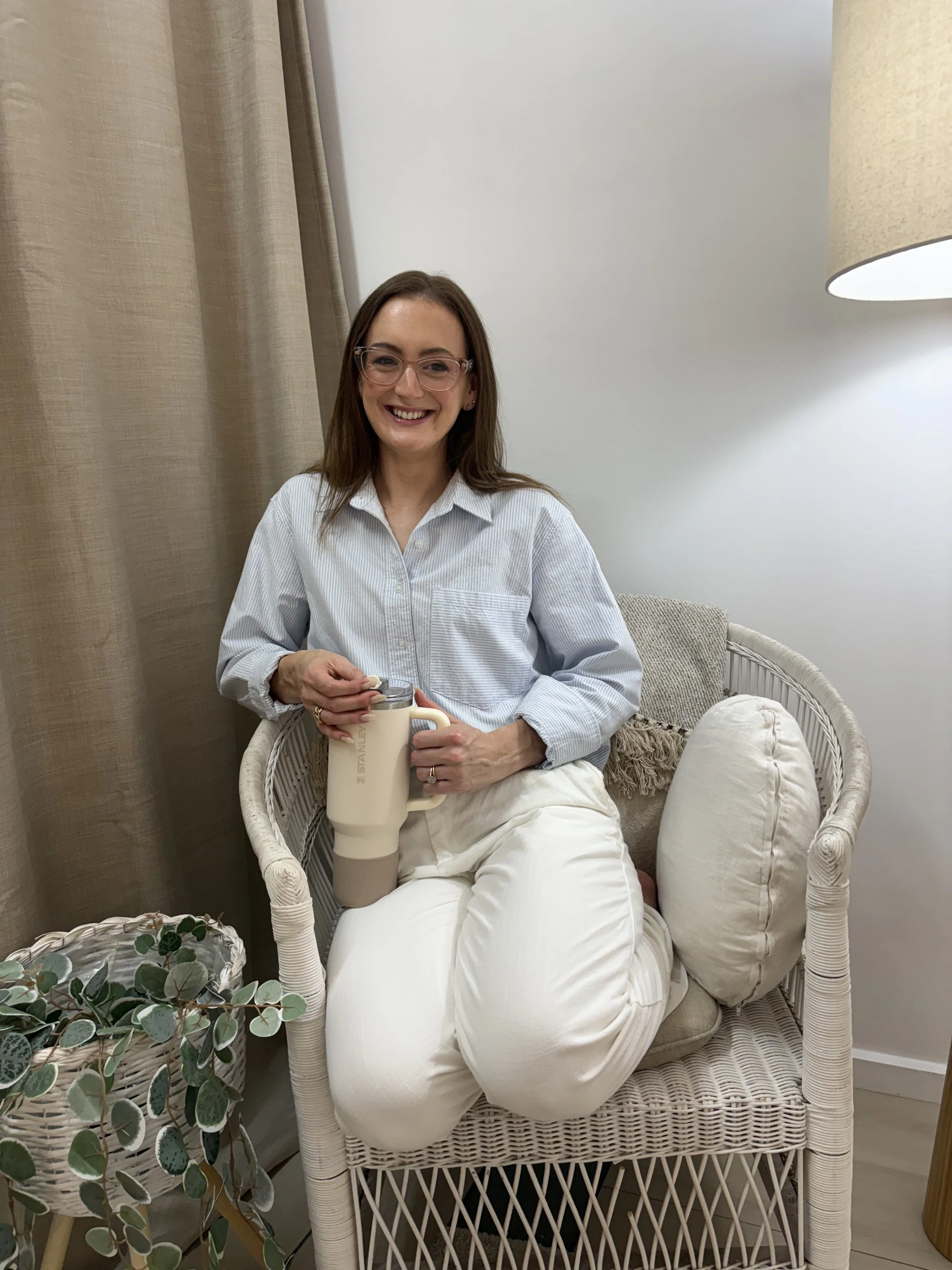 Jazmin Pursell sitting on knees on office chair, smiling, holding drink bottle