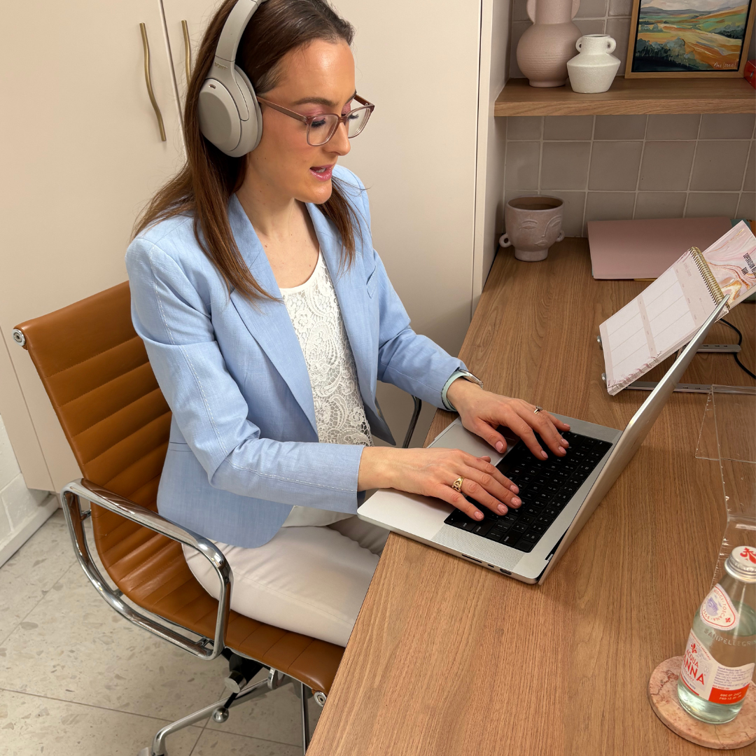 Jazmin Pursell sitting on desk on laptop, typing in home office