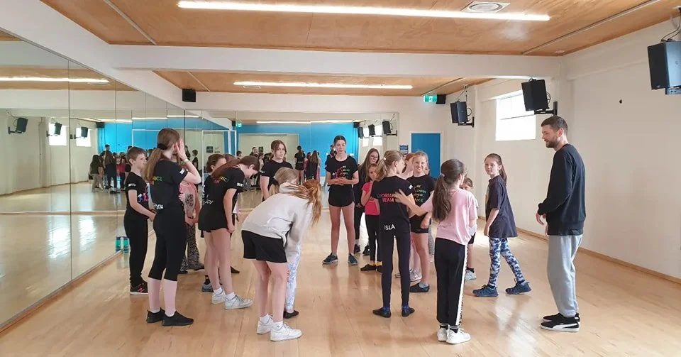 Dancers in a dance studio, standing in a group and talking