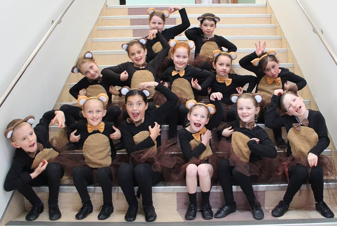 Group of young girls in matching animal costumes outfits posing on staircase.