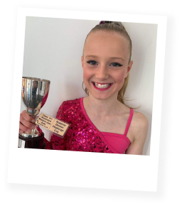 Young girl in pink dance costume holding a trophy and a certificate.