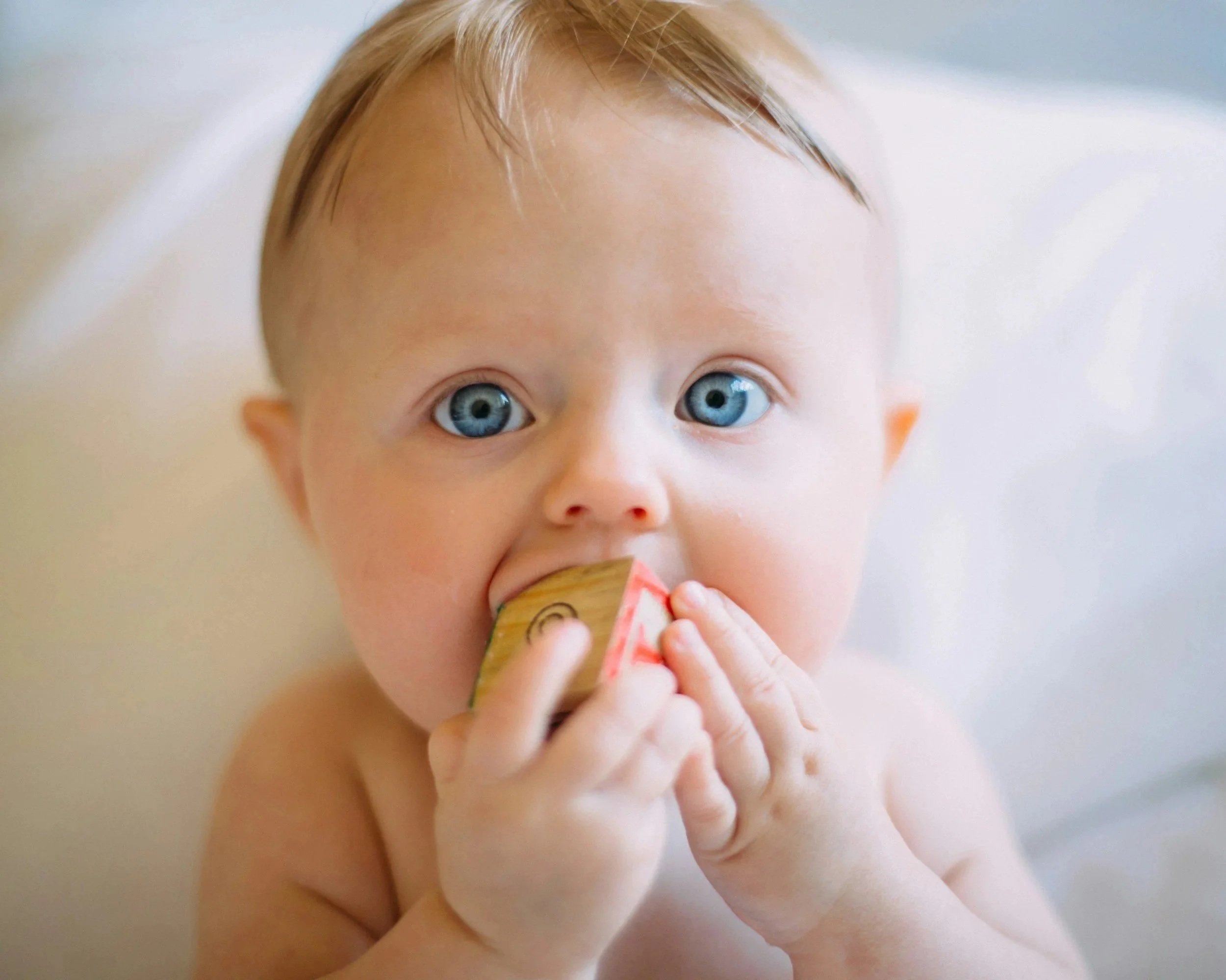 Happy baby holding a toy in their mouth, representing in-home lactation support in Colorado.