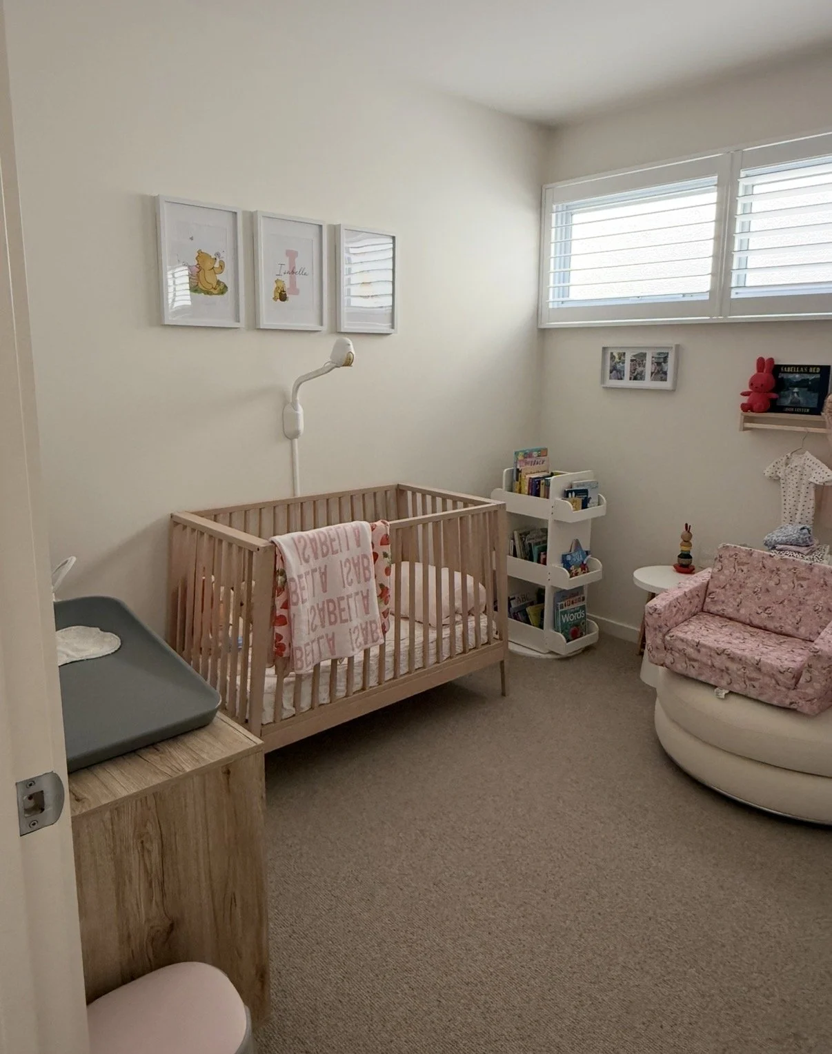 Children's nursery decor featuring a white and gray felt rainbow mobile with hanging plush elephants and stars, and a bunting banner of triangular flags with elephant patterns in tones of gray, white, and black, hanging on a white wall.
