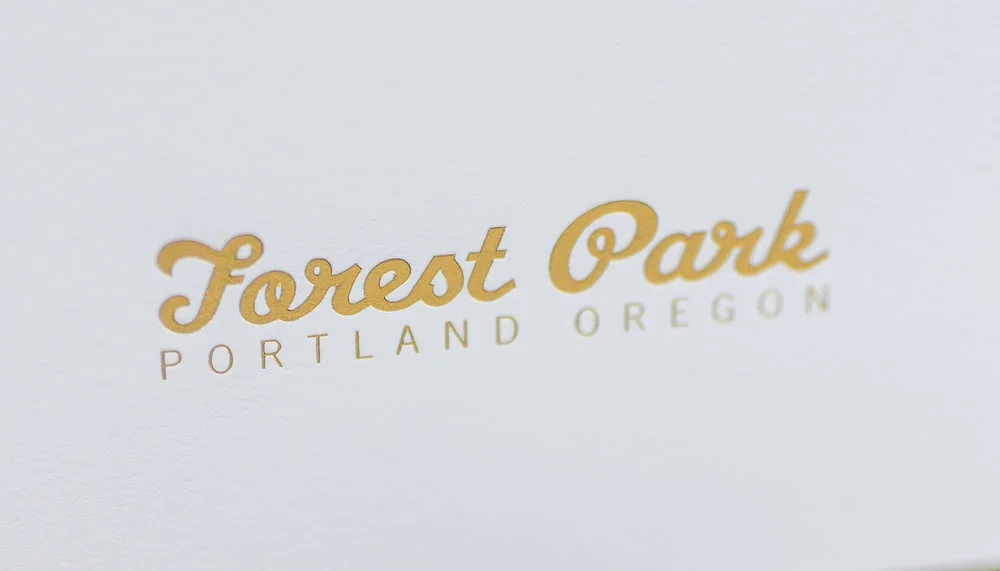 Sign reading 'Forest Park Portland Oregon' in gold lettering on a white background.