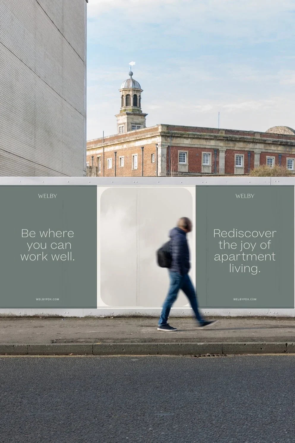Billboard with the messages 'Be where you can work well' and 'Rediscover the joy of apartment living', with a person walking past in an urban setting, and a historic building with a clock tower in the background.