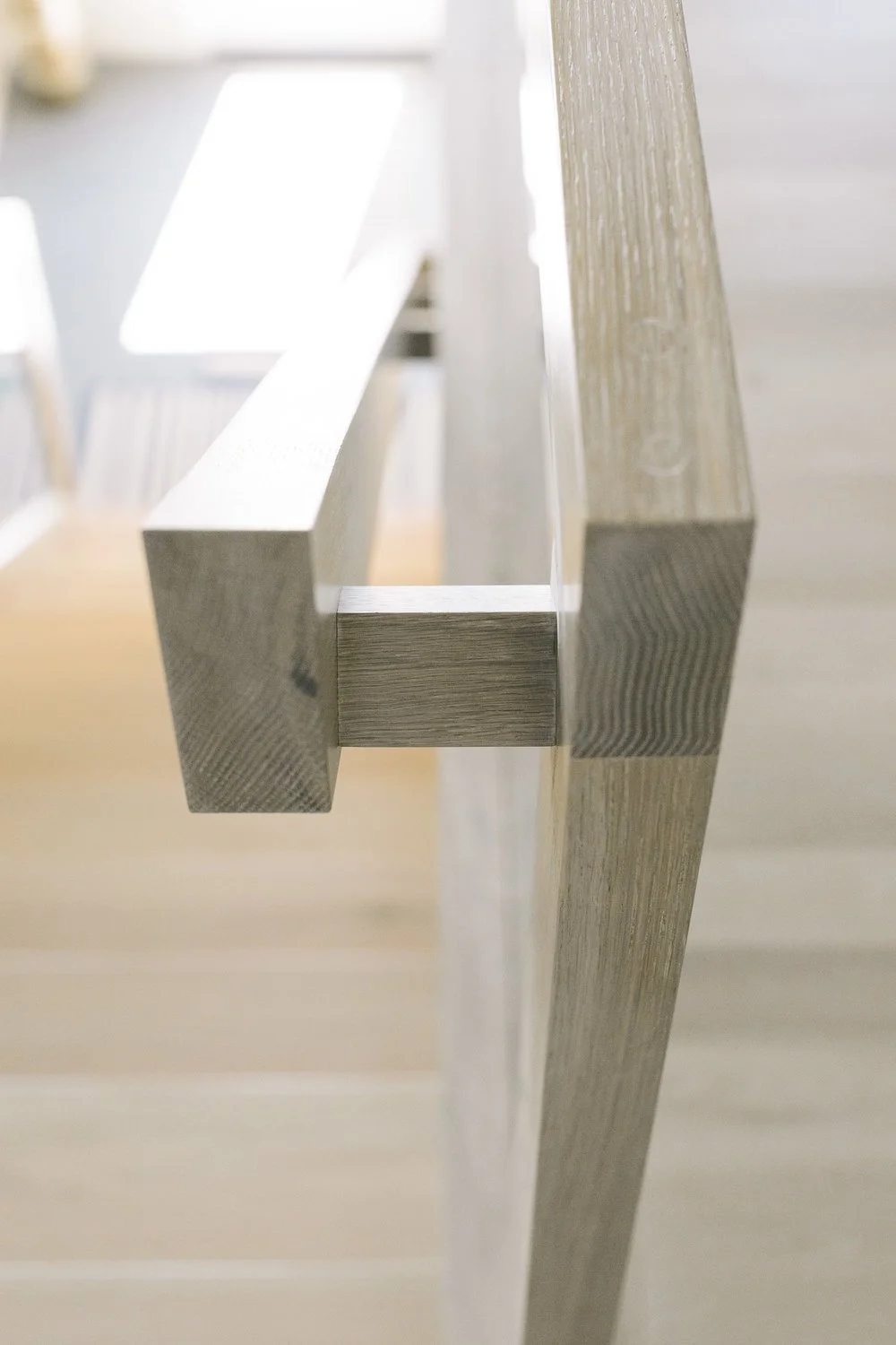 Close-up of a modern wooden staircase railing with a minimalist design, showing the corner joint of the banister from a side angle.