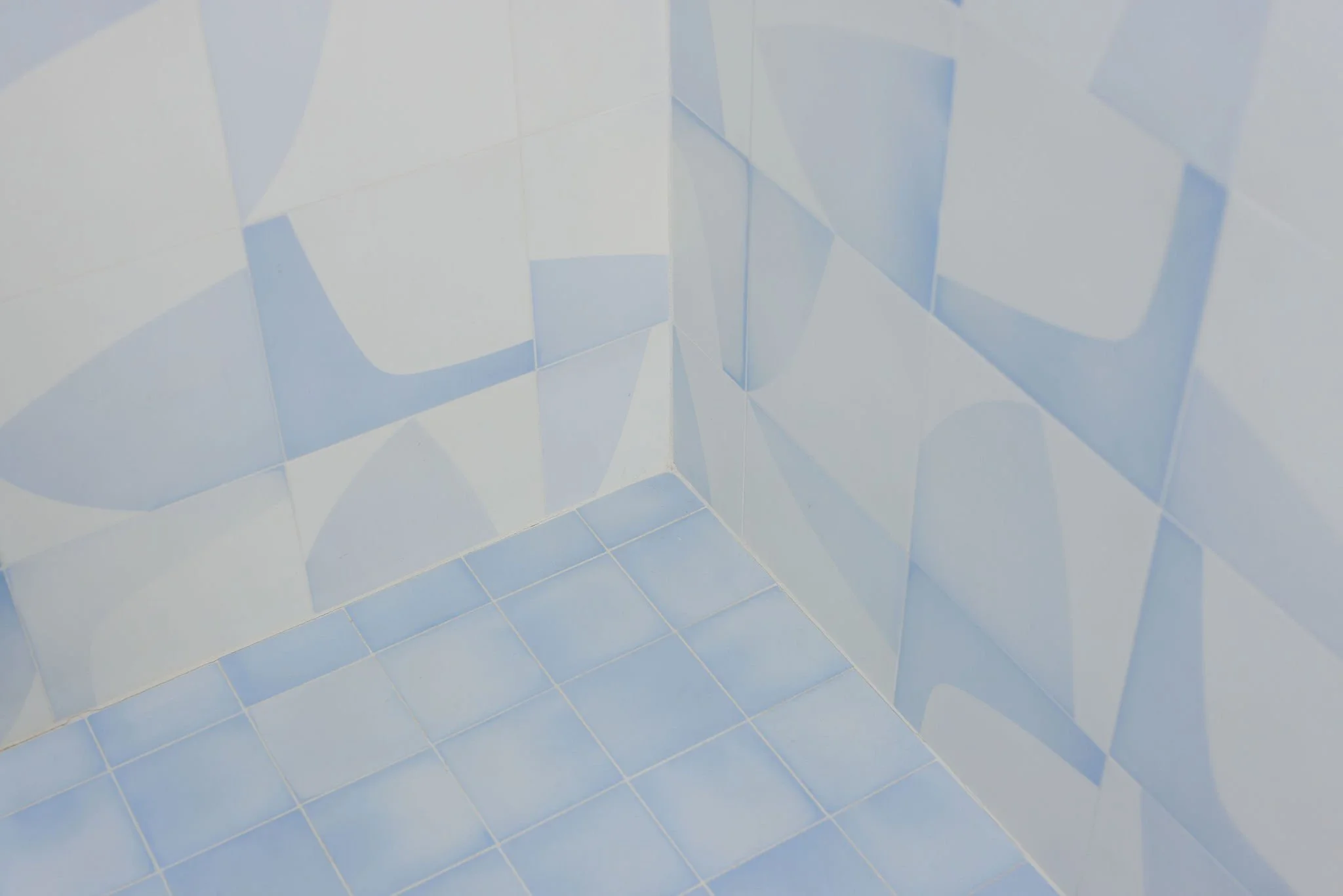 Close-up of a corner in a room with light blue and white tiled walls and floor.