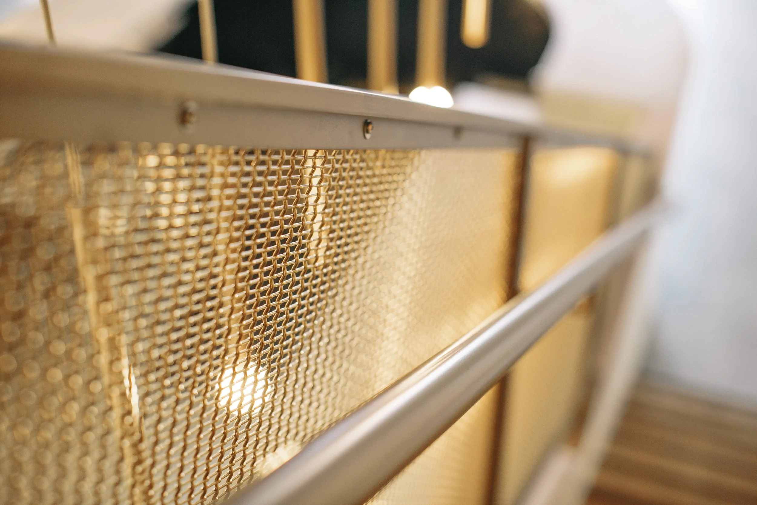 Close-up of a metallic cabinet or drawer with a gold-colored mesh panel and a metal frame.
