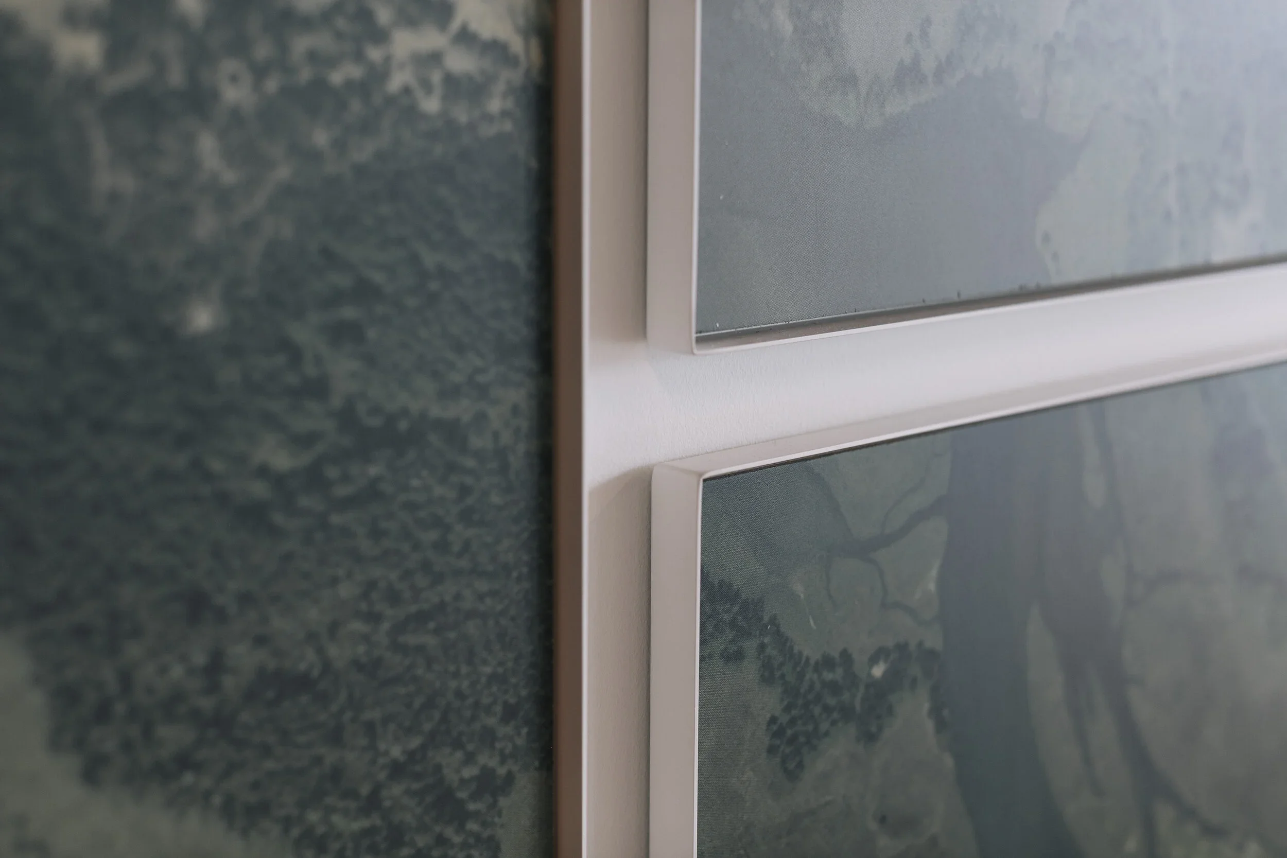 Close-up of an electronic display screen with a weather map, framed in a white border, mounted on a textured dark green wall.