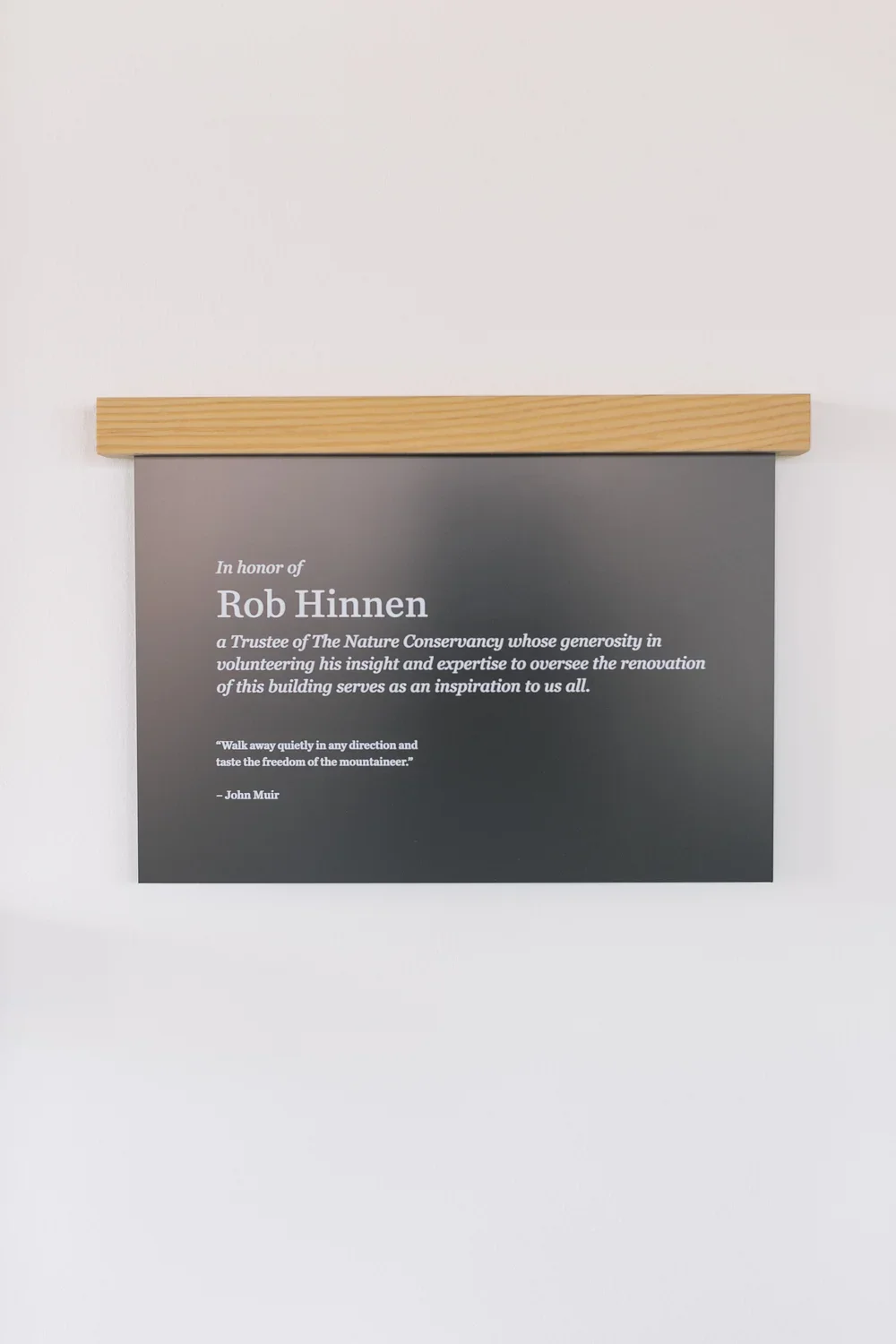 Plaque honoring Rob Hinnen, a trustee of The Nature Conservancy, with a quote by John Muir, mounted on a wall with a wooden top.