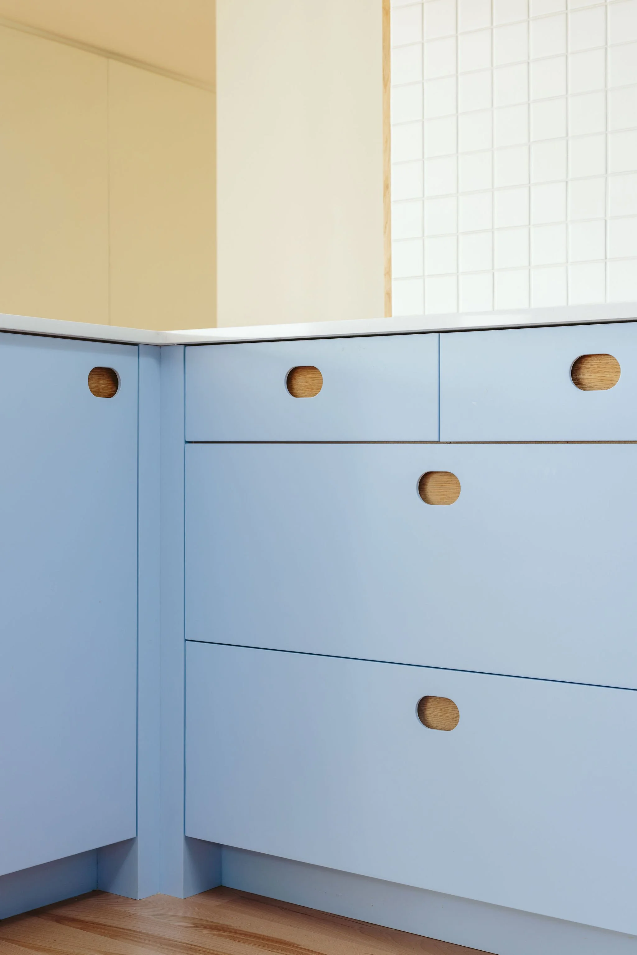 Close-up of a light blue cabinetry with oval-shaped cutout handles in a modern kitchen.