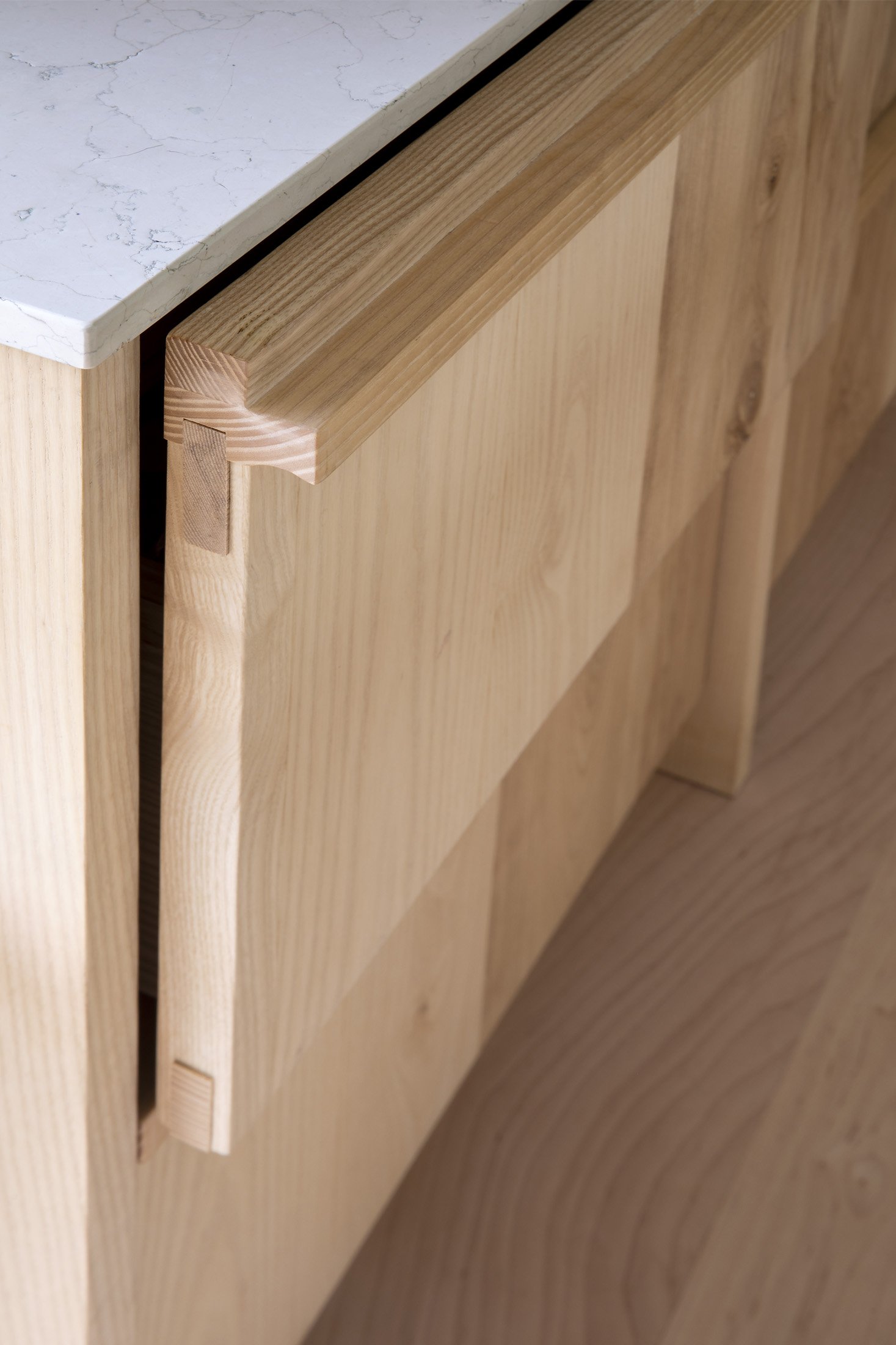 Close-up of a wooden cabinet with a natural finish and a marble top.