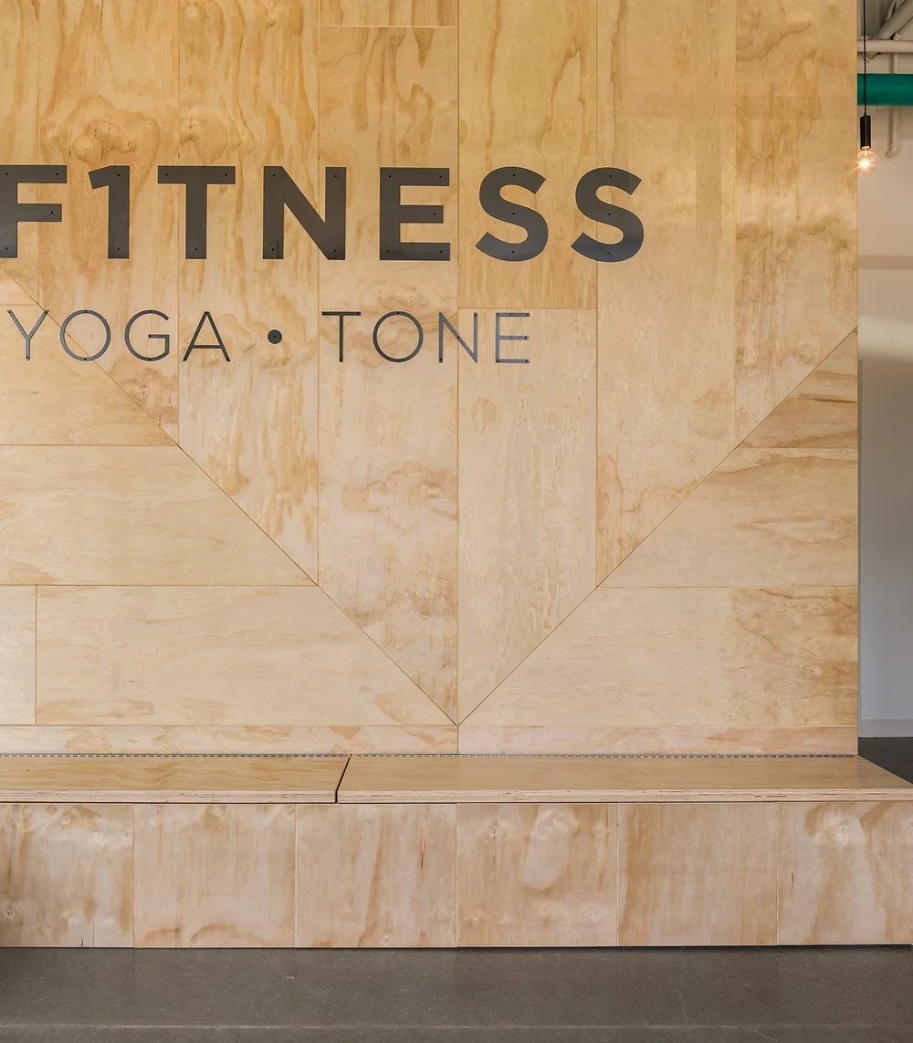 Wood-paneled wall with the words 'FITNESS', 'YOGA', and 'TONE' displayed.