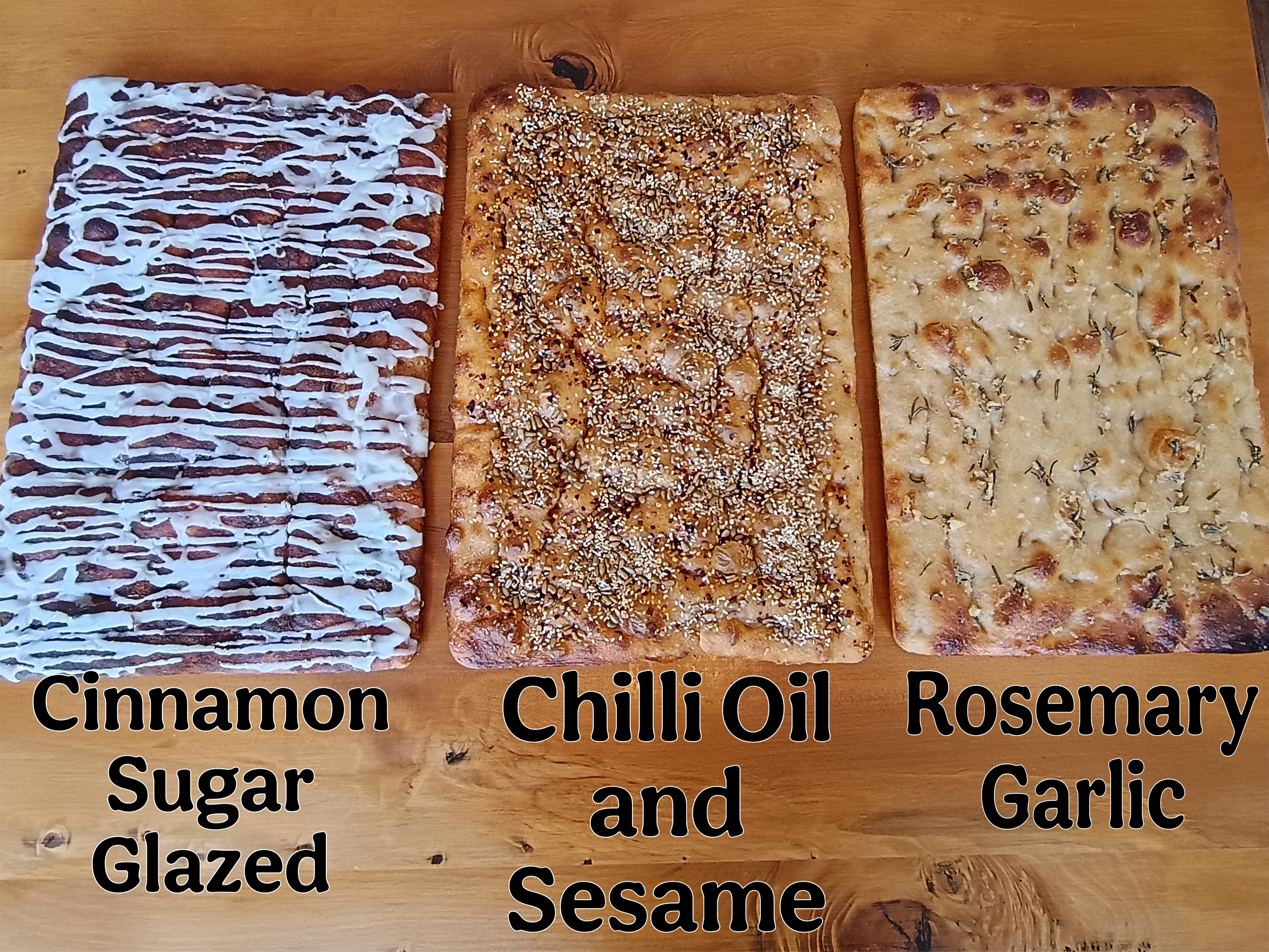 Three whole focaccia sourdough bread slabs; cinnamon sugar glazed, chilli oil sesame, rosemary garlic