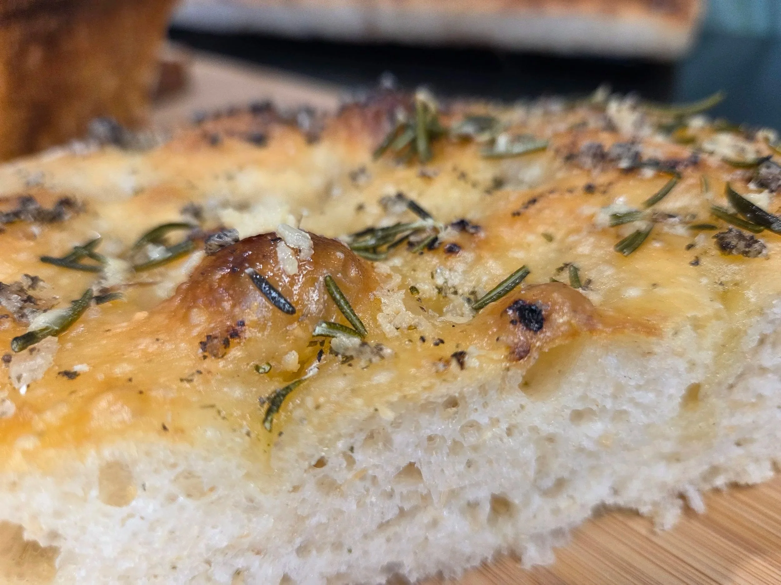 Focaccia slab slice with close up view of savoury rosemary, garlic and salt flavours, baked fresh by Kapiti Delicious Doughs and delivered across the Kapiti Coast