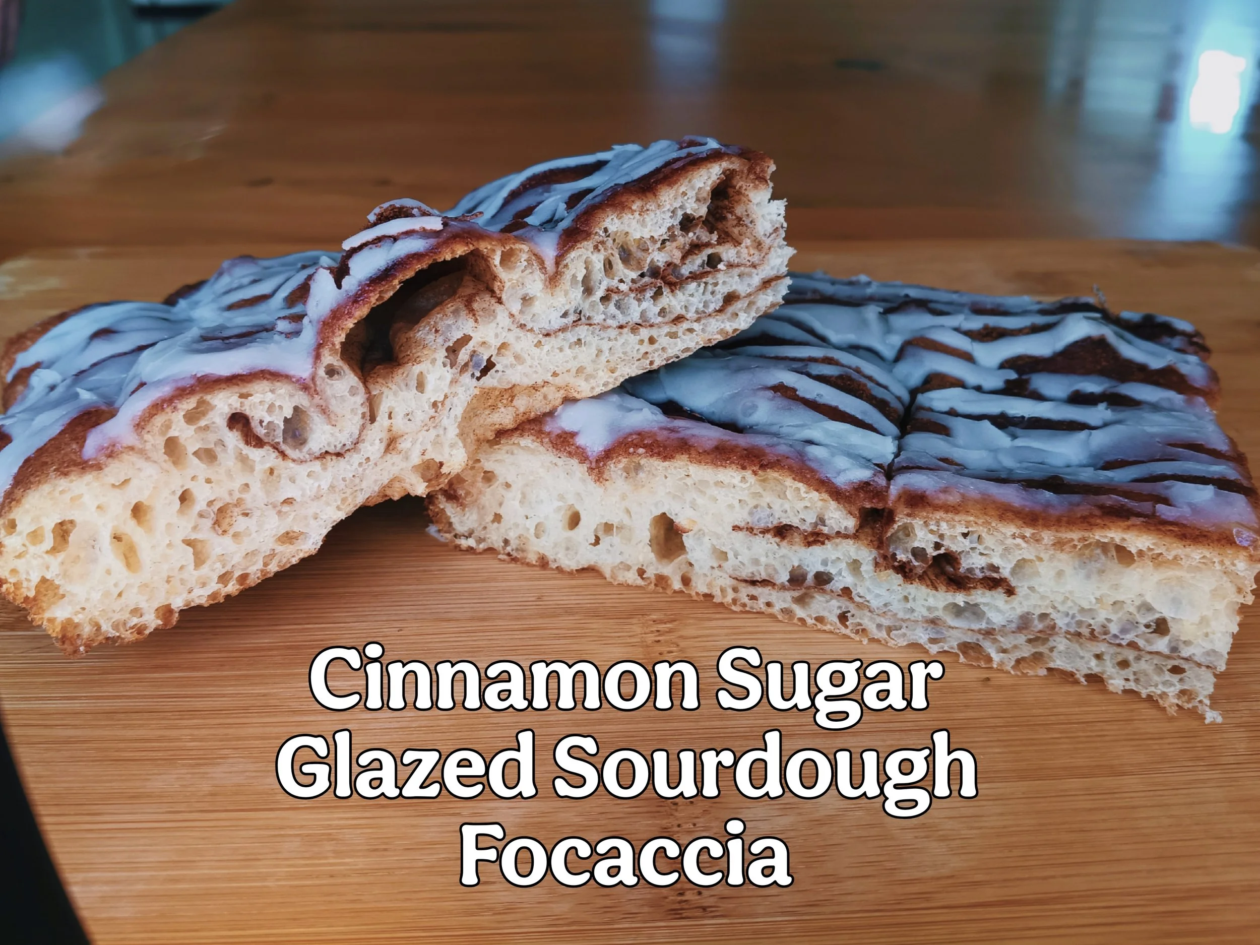 Cross cut section of cinnamon sugar glazed sourdough focaccia bread with streaks of cinnamon thorughout the bread and white dairy-free glaze drizzle on top.