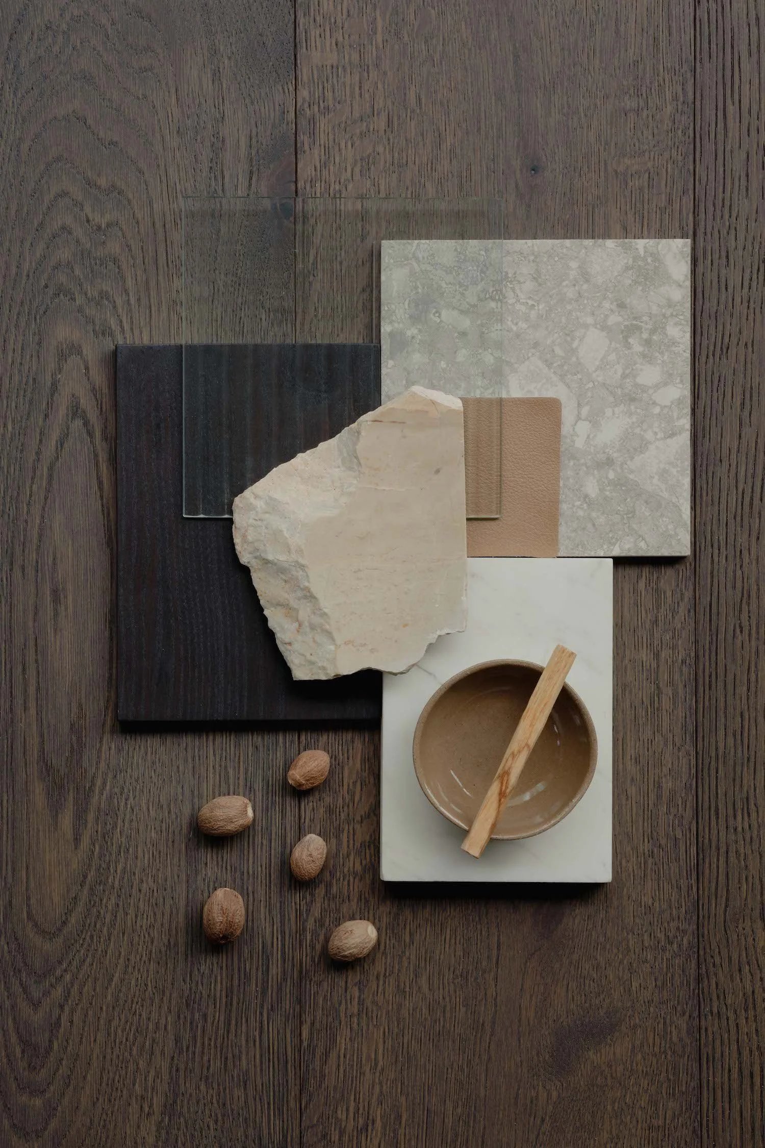 Arrangement of various natural materials including stone, wood, and paper on a wooden surface, with almonds scattered nearby.