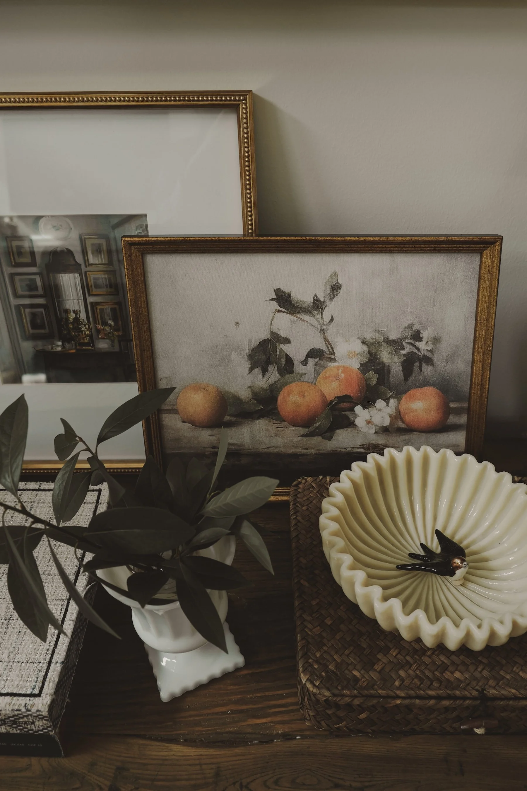 Decorative interior display with artwork, potted plant, and ceramic bowl.