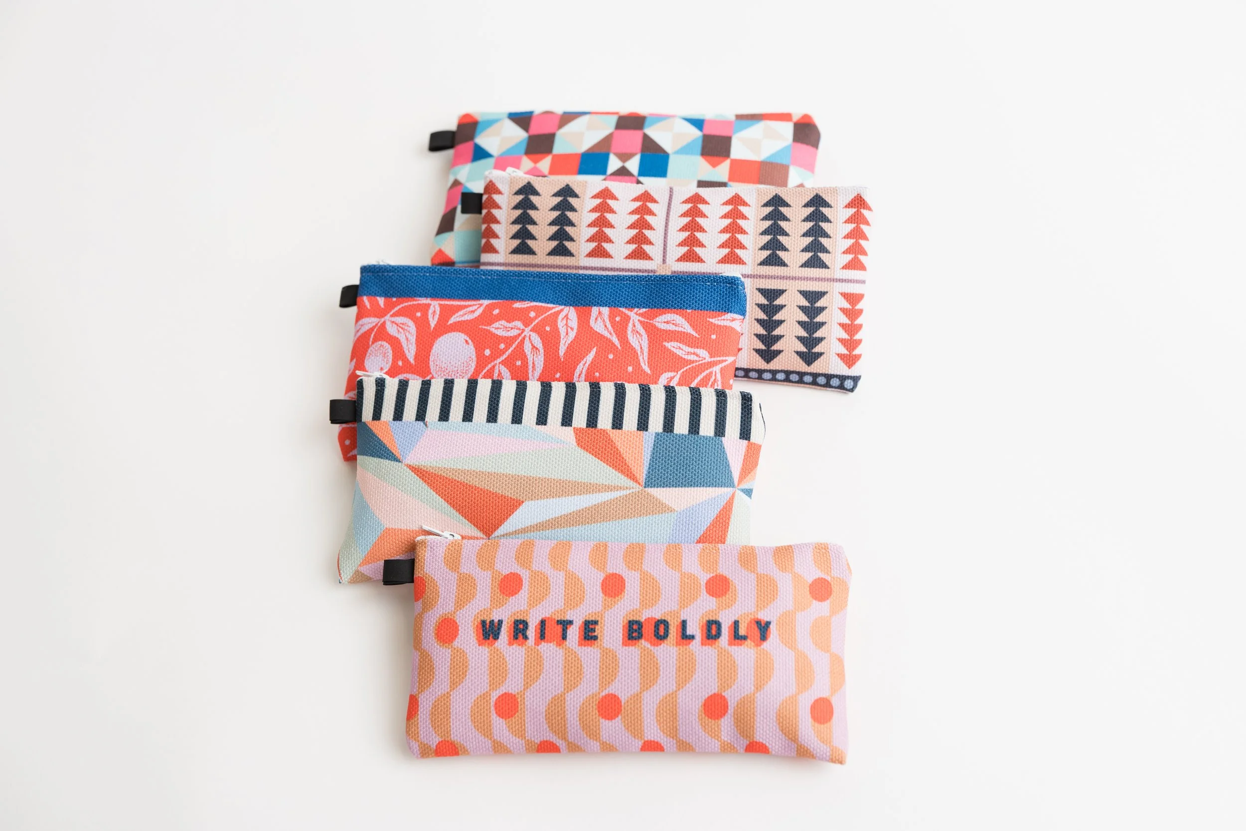 Five colorful fabric zippered pouches lined up vertically with various geometric and abstract patterns.