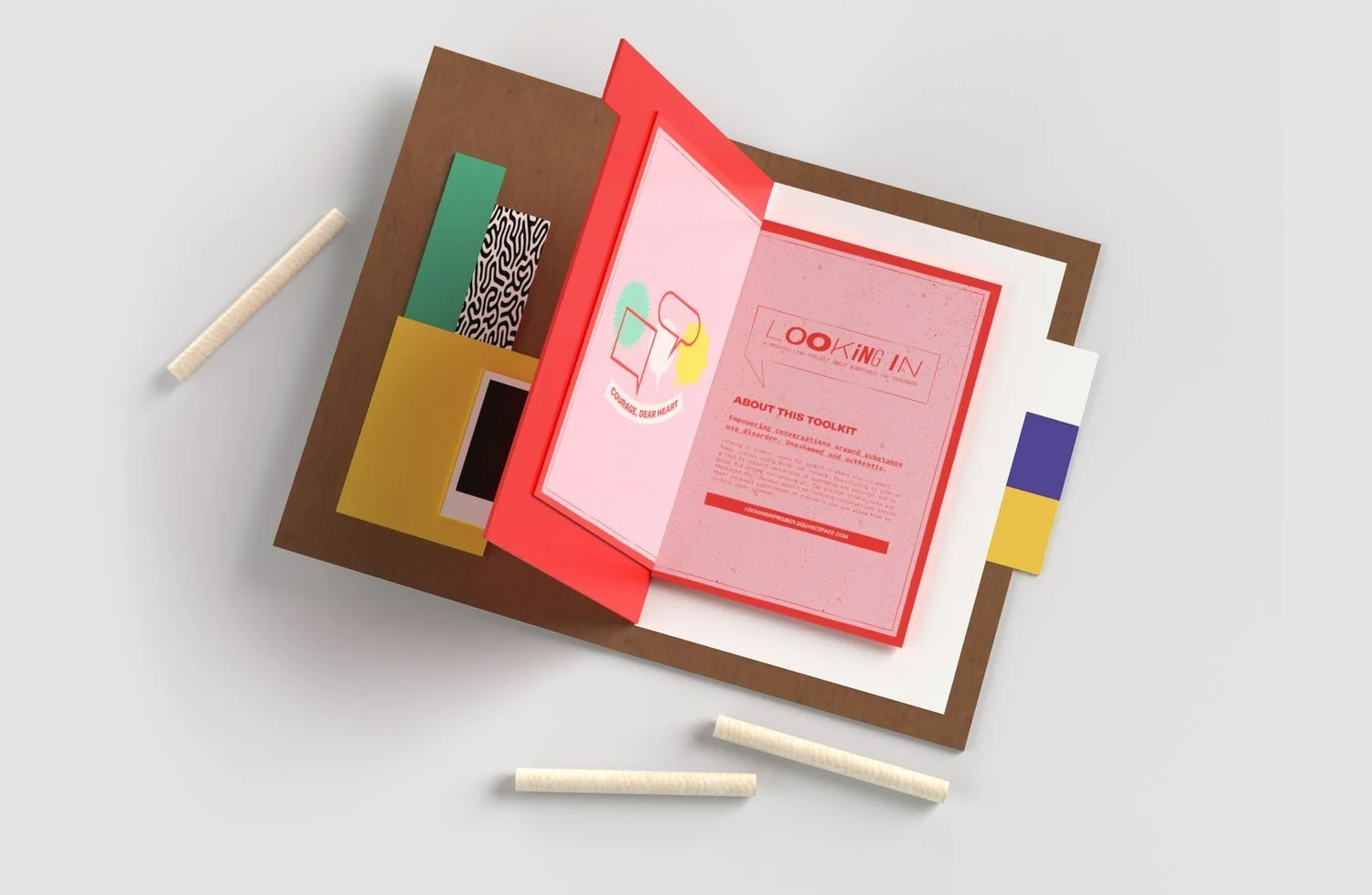 Open toolkit binder with colorful papers, a booklet titled 'Looking In,' and four white chalks on a white surface.