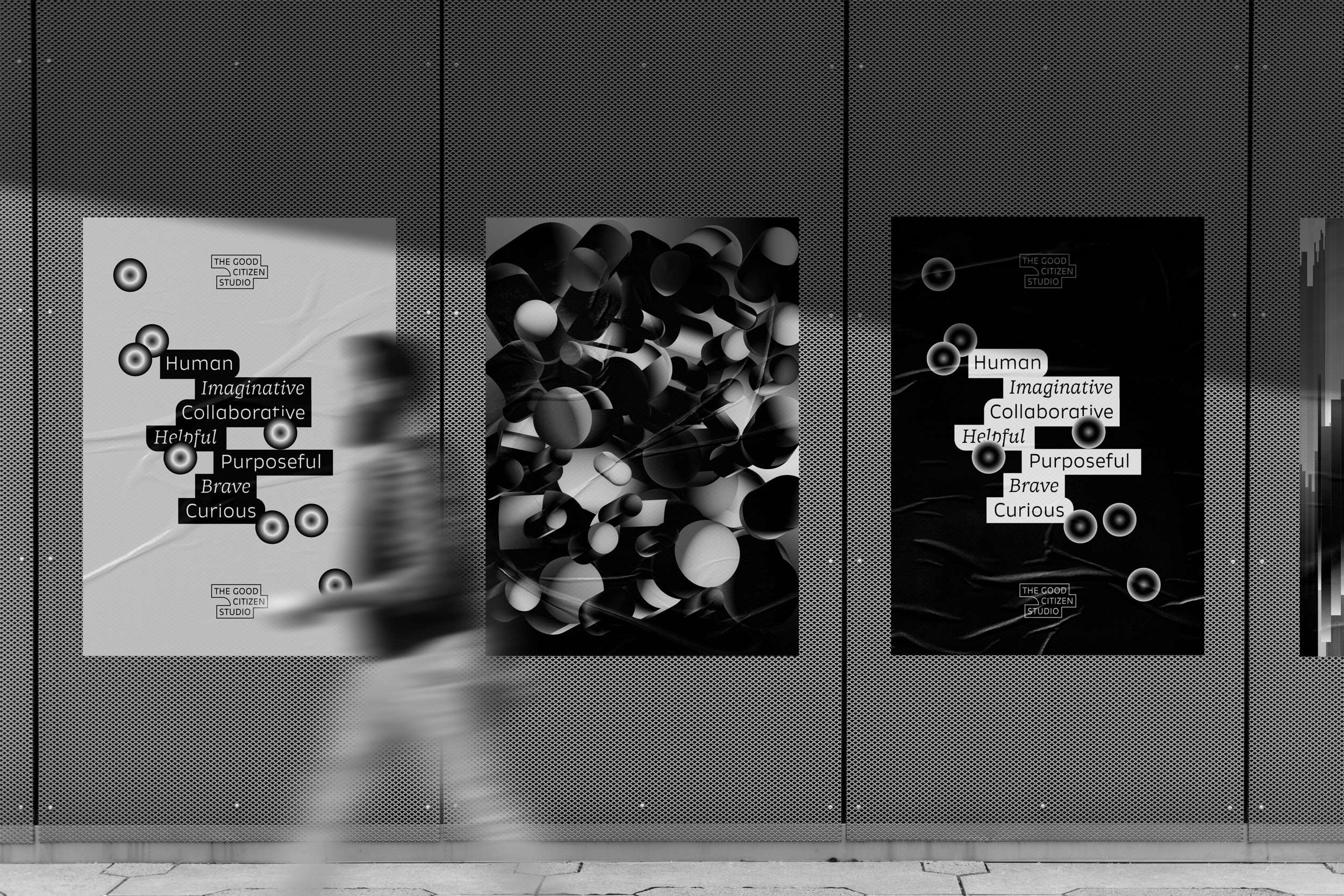 Black and white posters on a textured wall, featuring text about human qualities such as imagination, collaboration, helpfulness, purposefulness, bravery, and curiosity, with blurred person walking past.