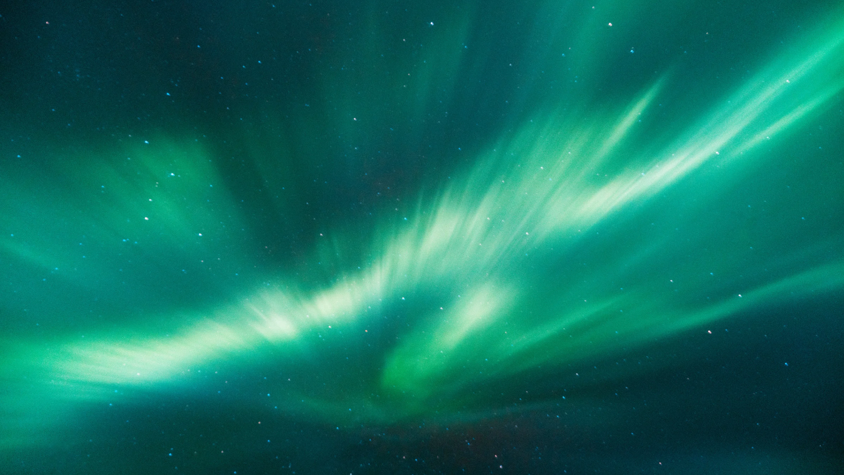 Northern lights in the night sky with green streaks and stars visible