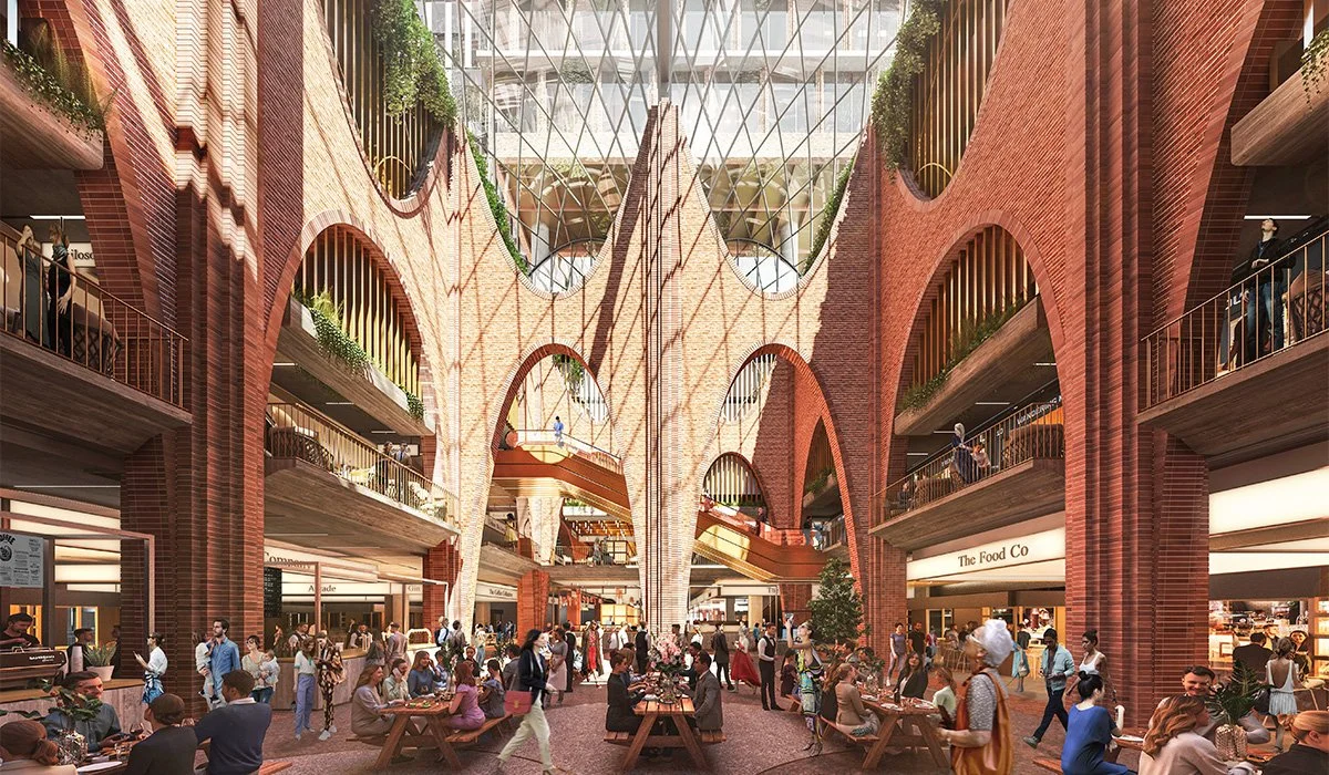 Interior of a modern shopping mall with red brick arches, open walkways, and people dining and shopping.