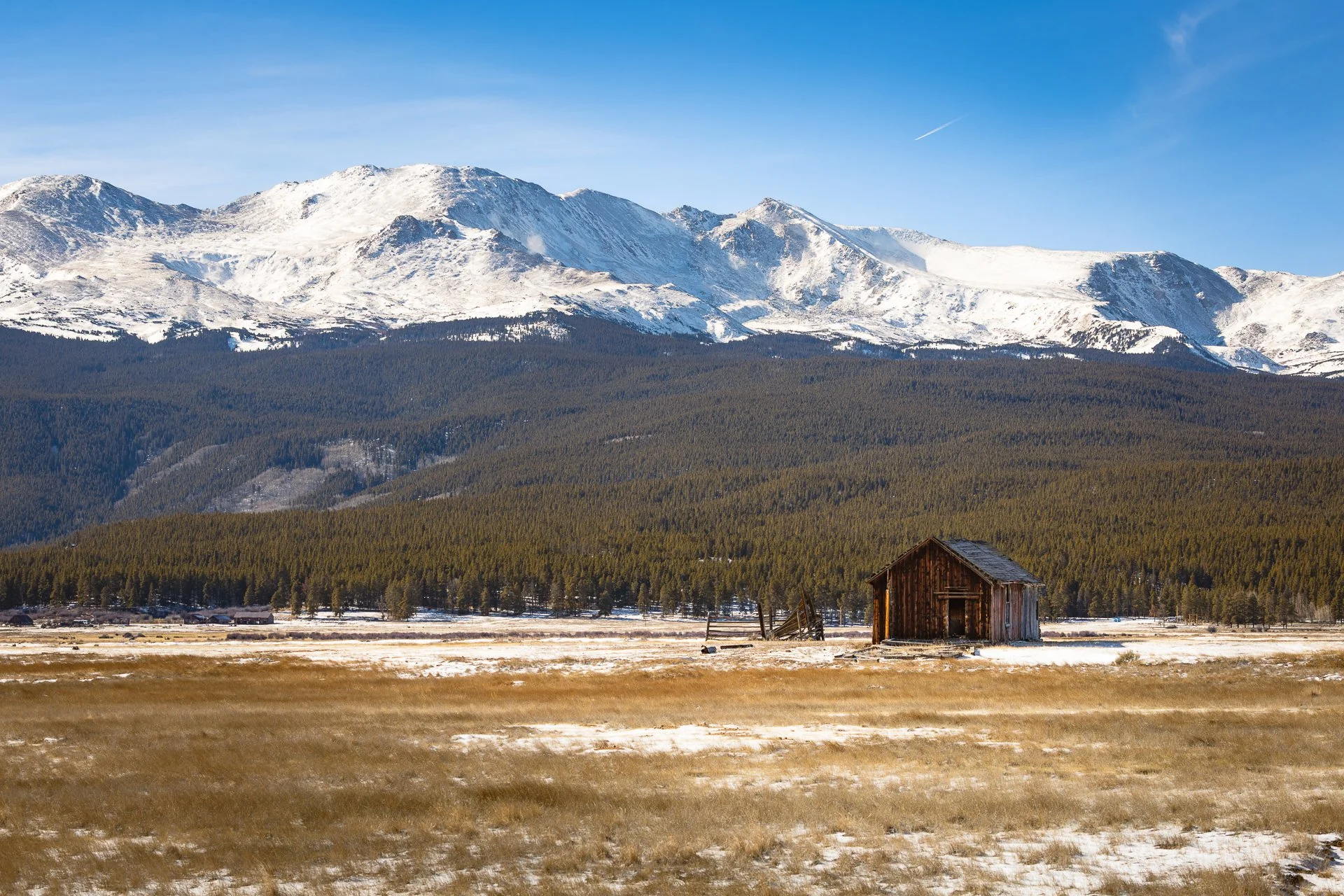 Old wooden cabin in a snowy valley near Leadville, Colorado with the Sawatch Range in the background.