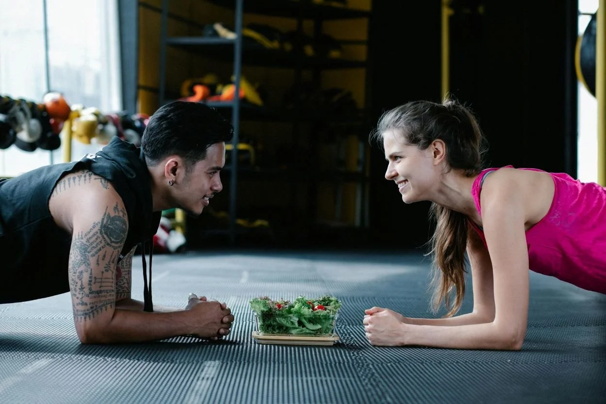 during fitness coaching or two people doing a plank there is a salad in the centre to discuss nutrition coaching