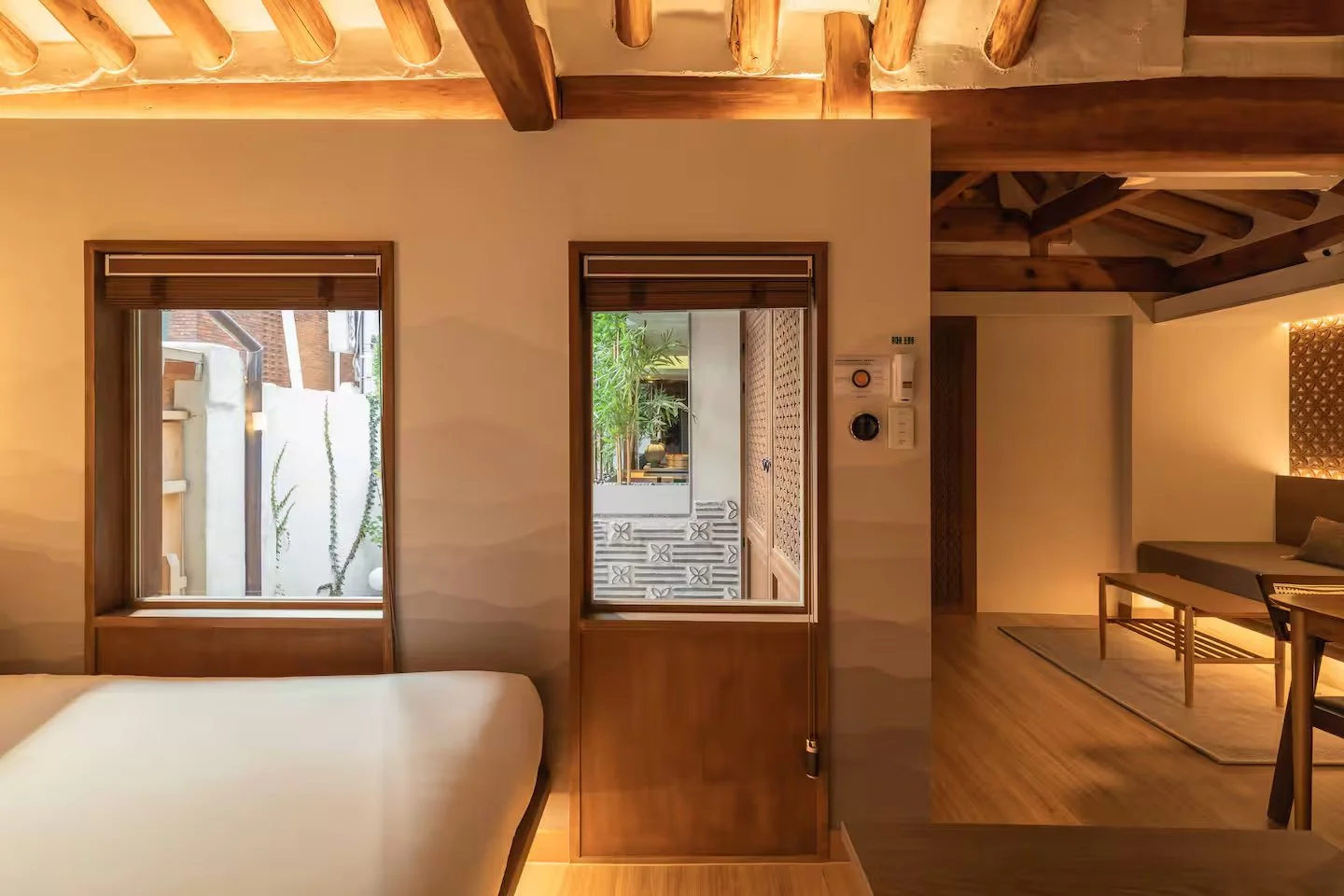 Bedroom interior at Jeonggaheon hanok featuring a view of the bamboo garden through a traditional floor-to-ceiling glass window.