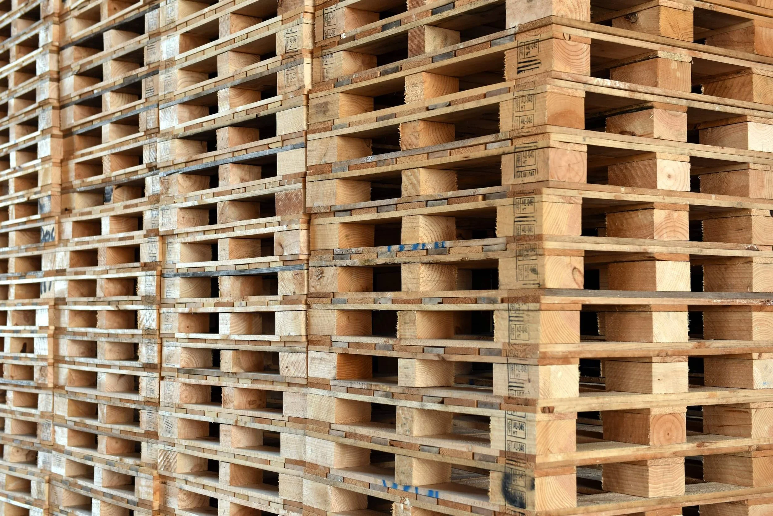 A large stack of wooden pallets arranged in columns.