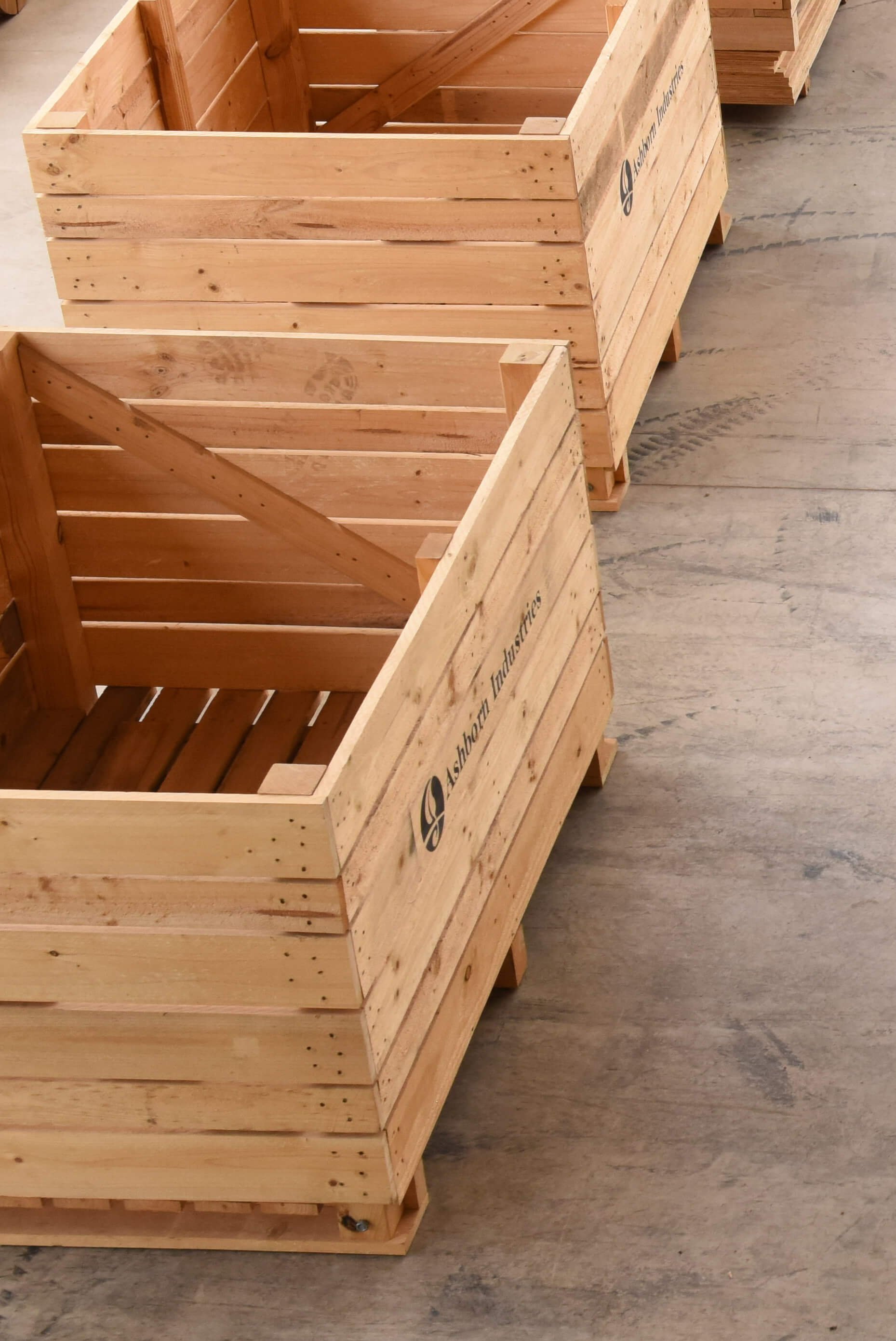 Empty wooden crates with the logo 'Ashbor Industries' on the side, placed on a wooden floor.