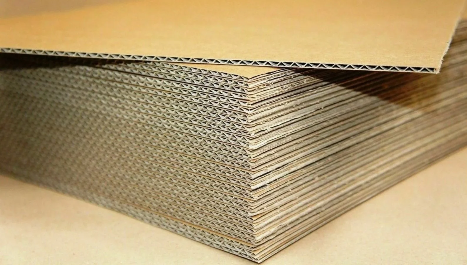 Close-up of stacked corrugated cardboard sheets, showing the wavy inner structure.